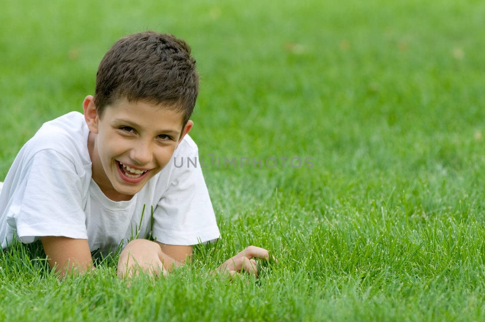 a boy is smiling on the green grass