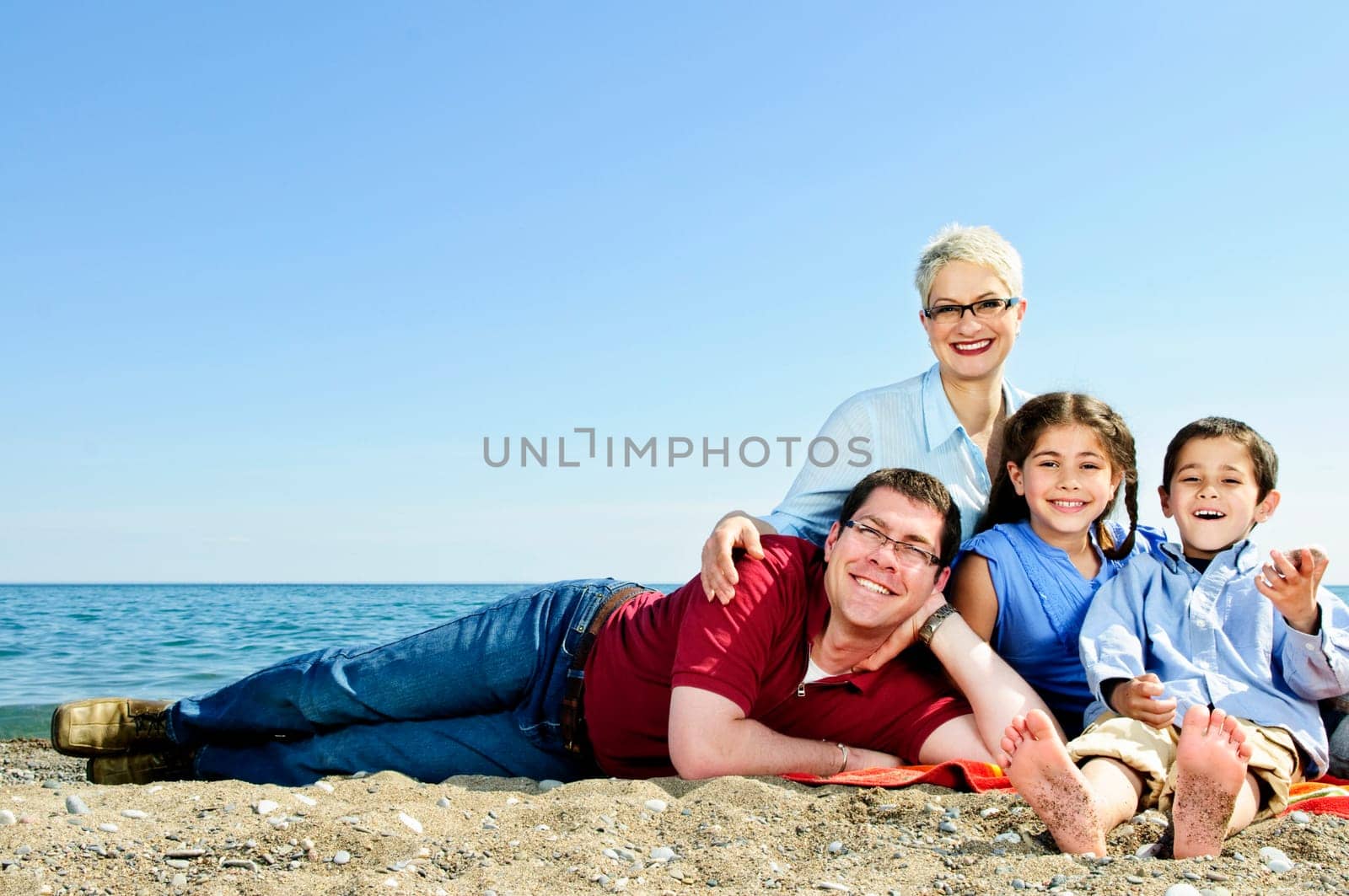 Happy family laying on towel at sandy beach