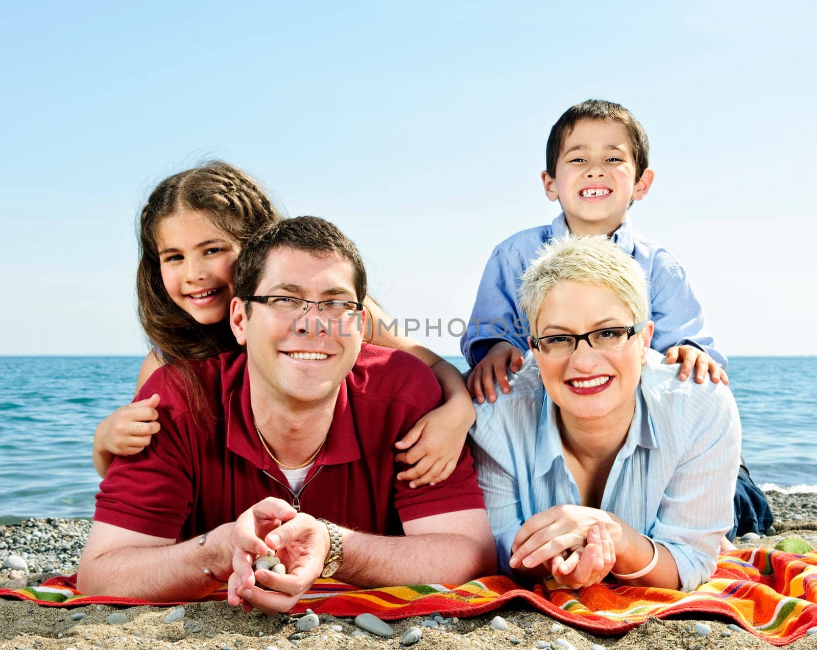 Happy family laying on towel at sandy beach