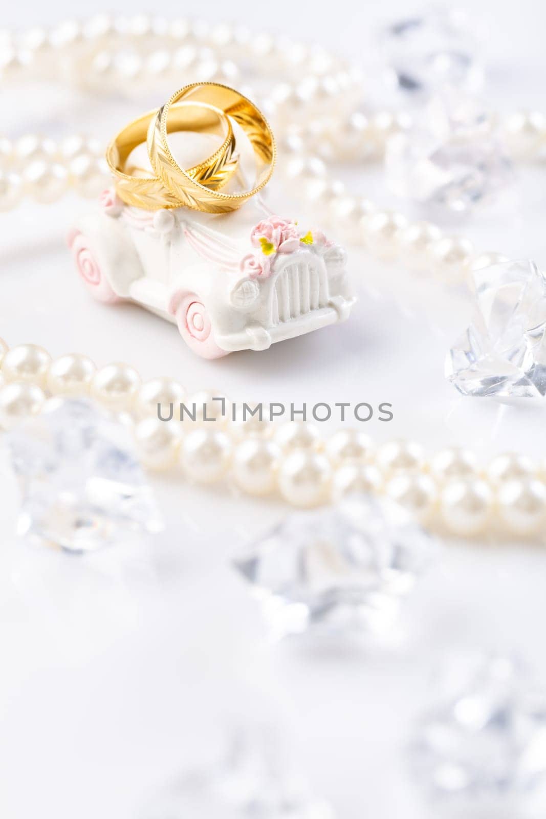 Two wedding rings on small vintage car with pearl necklace.