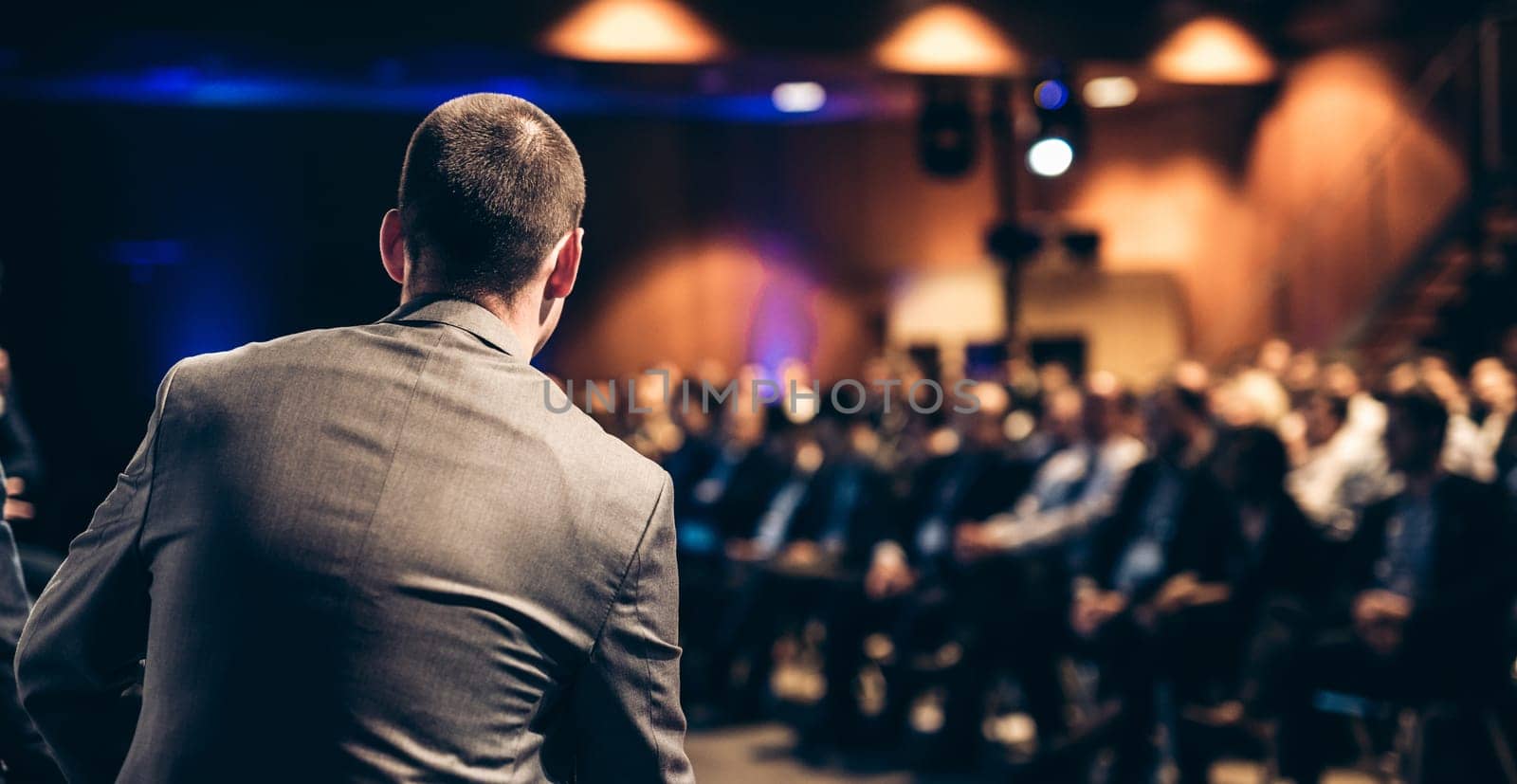 Speaker giving a talk on corporate business conference. Unrecognizable people in audience at conference hall. Business and Entrepreneurship event.