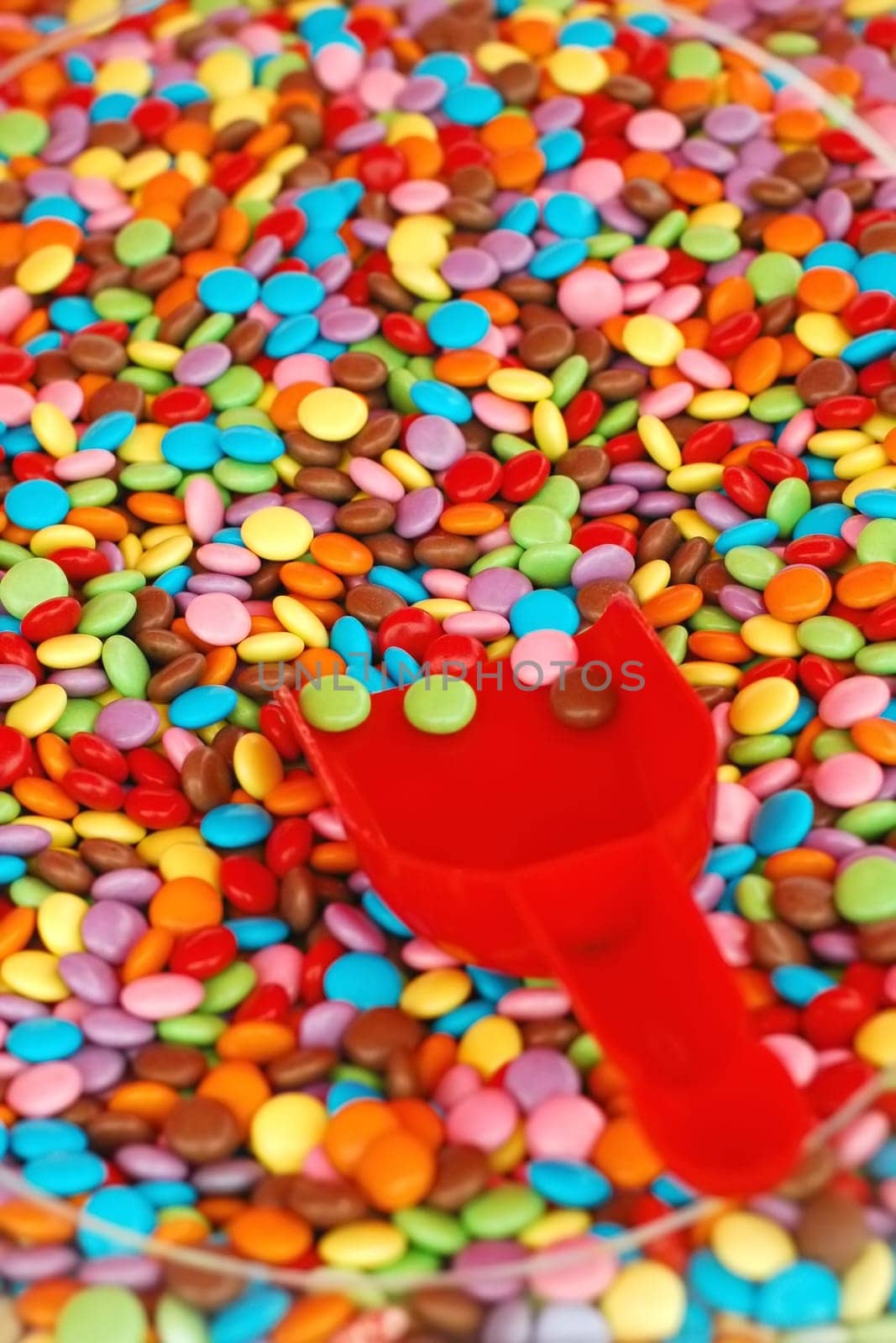 multi-colored candy coated confectionery in a bowl with scoop