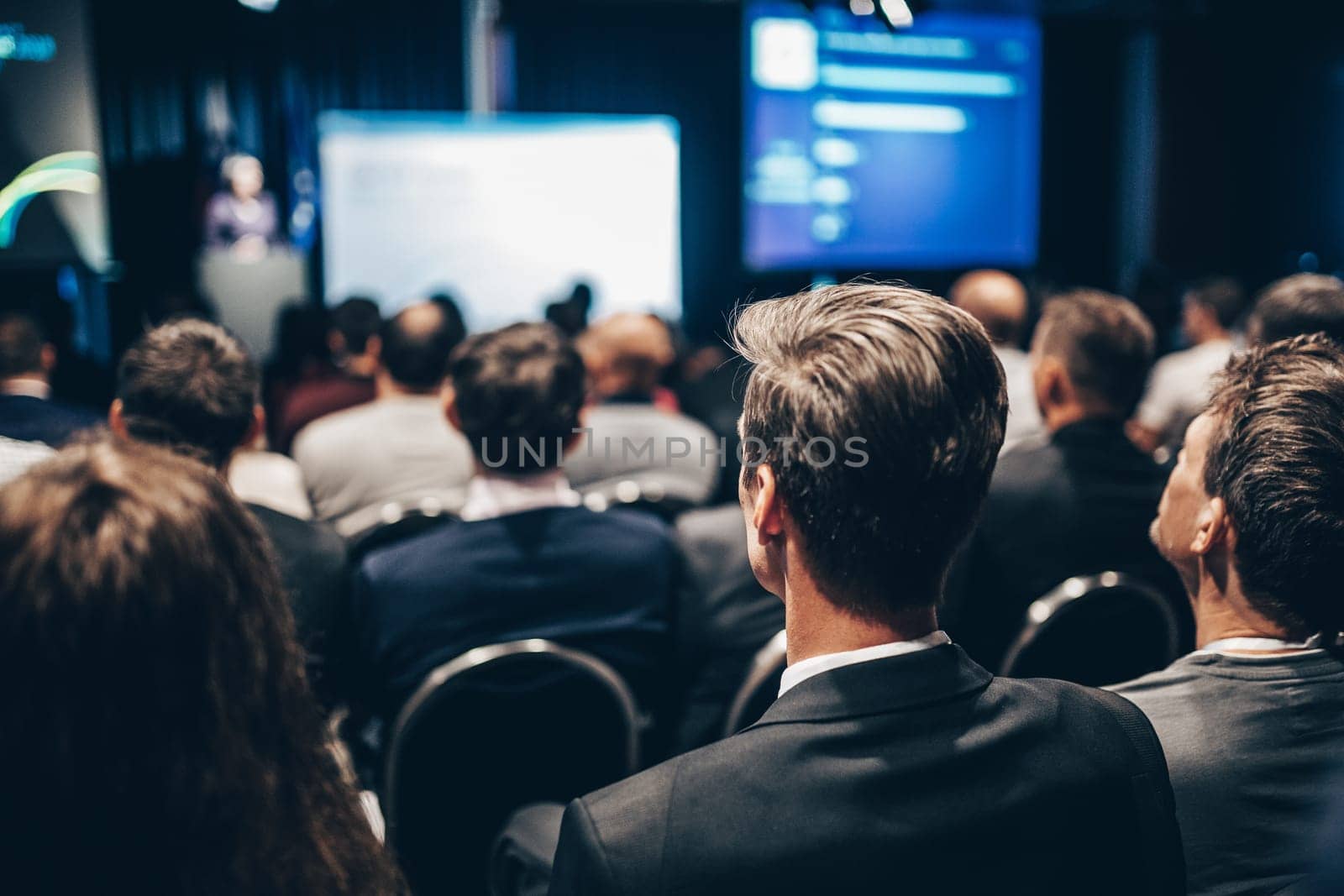 Speaker giving a talk in conference hall at business event. Rear view of unrecognizable people in audience at the conference hall. Business and entrepreneurship concept
