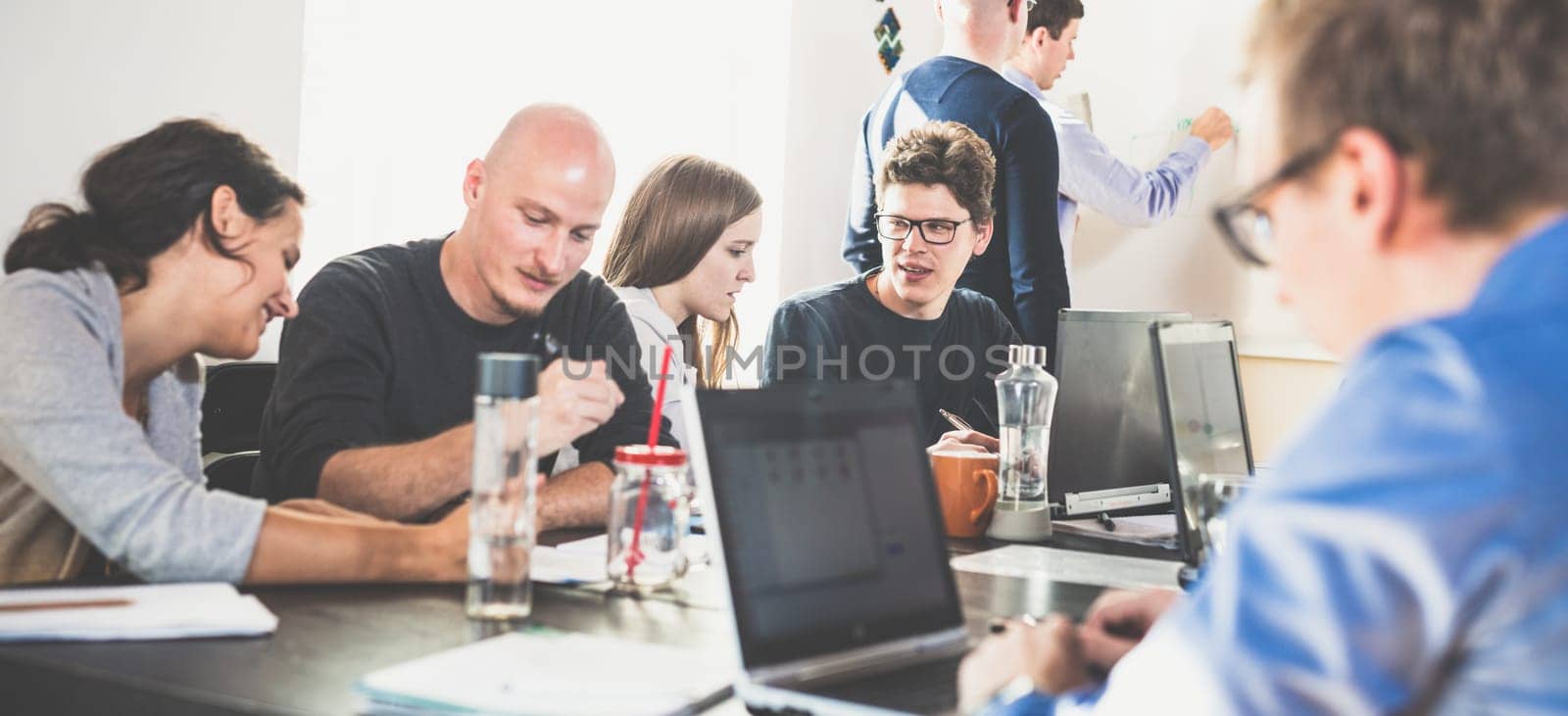 Startup business and entrepreneurship problem solving. Young AI programmers and IT software developers team brainstorming and programming on desktop computer in startup company share office space.