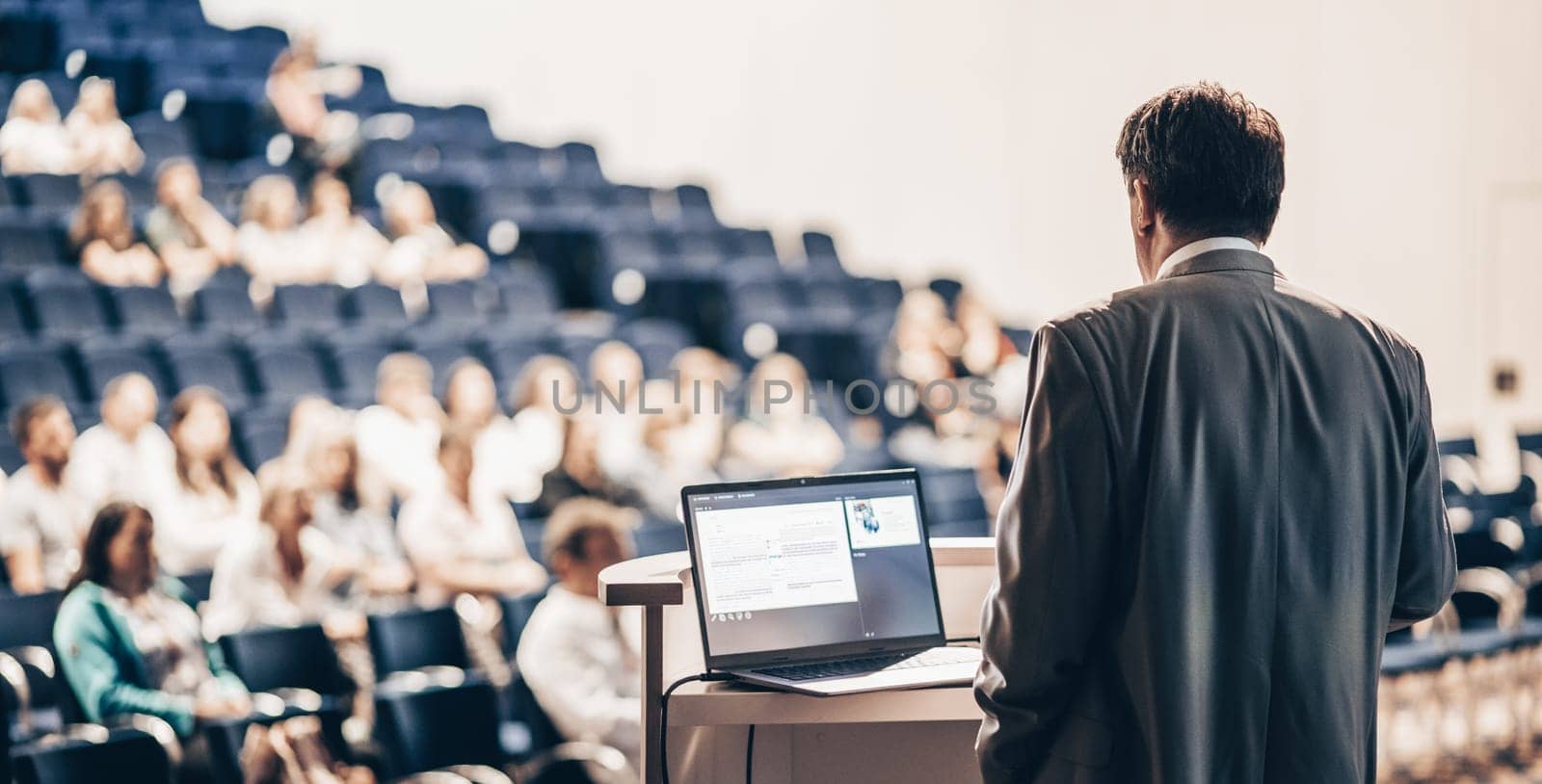 Speaker giving a talk on corporate business conference. Unrecognizable people in audience at conference hall. Business and Entrepreneurship event.