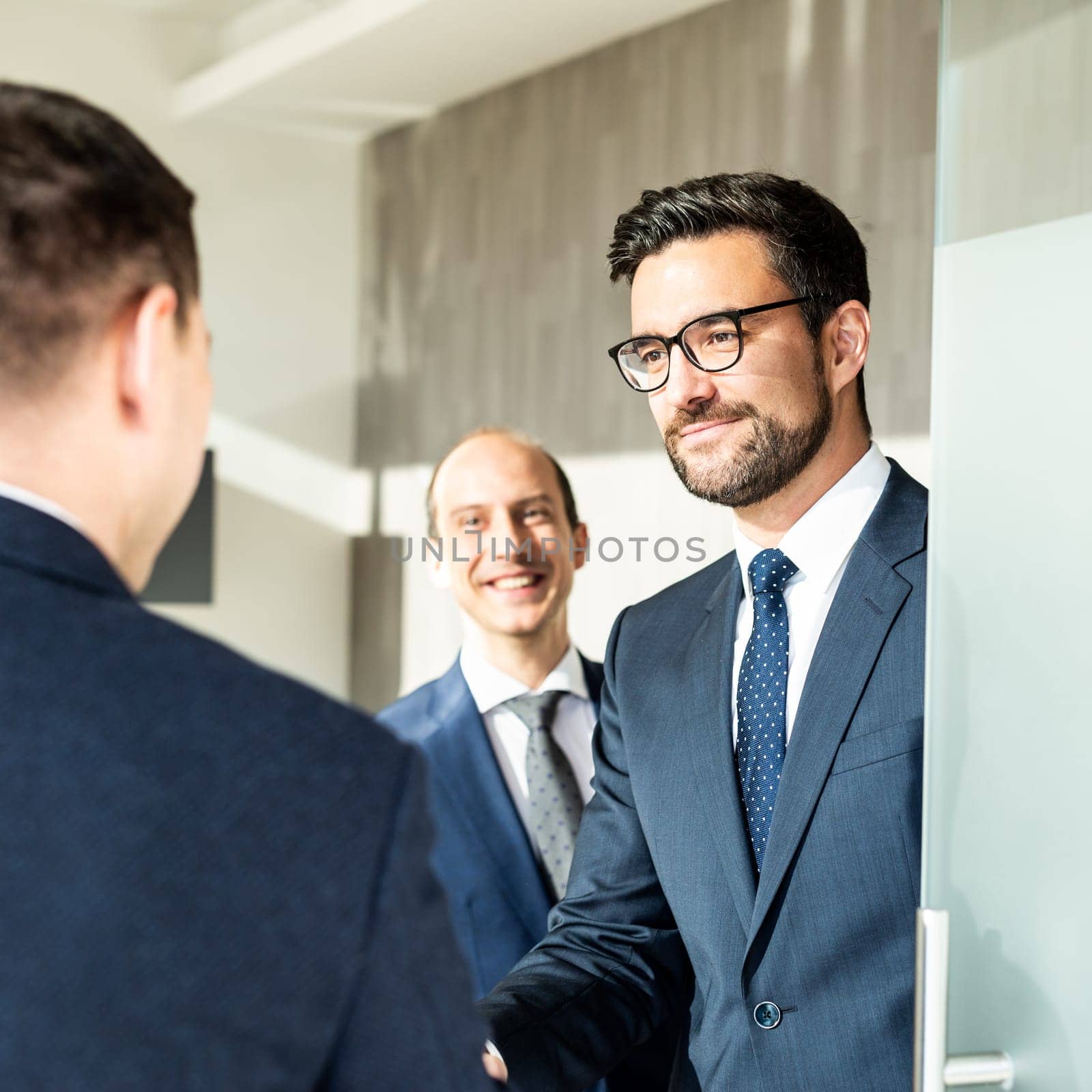 Group of confident business people greeting with a handshake at business meeting in modern office.