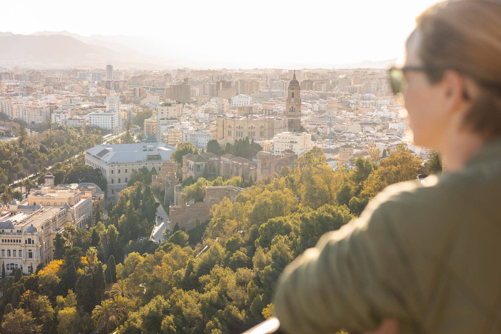 Bolnde female touris enjoying amazing panoramic aerial view of Malaga city historic center, Coste del Sol, Andalucia, Spain.