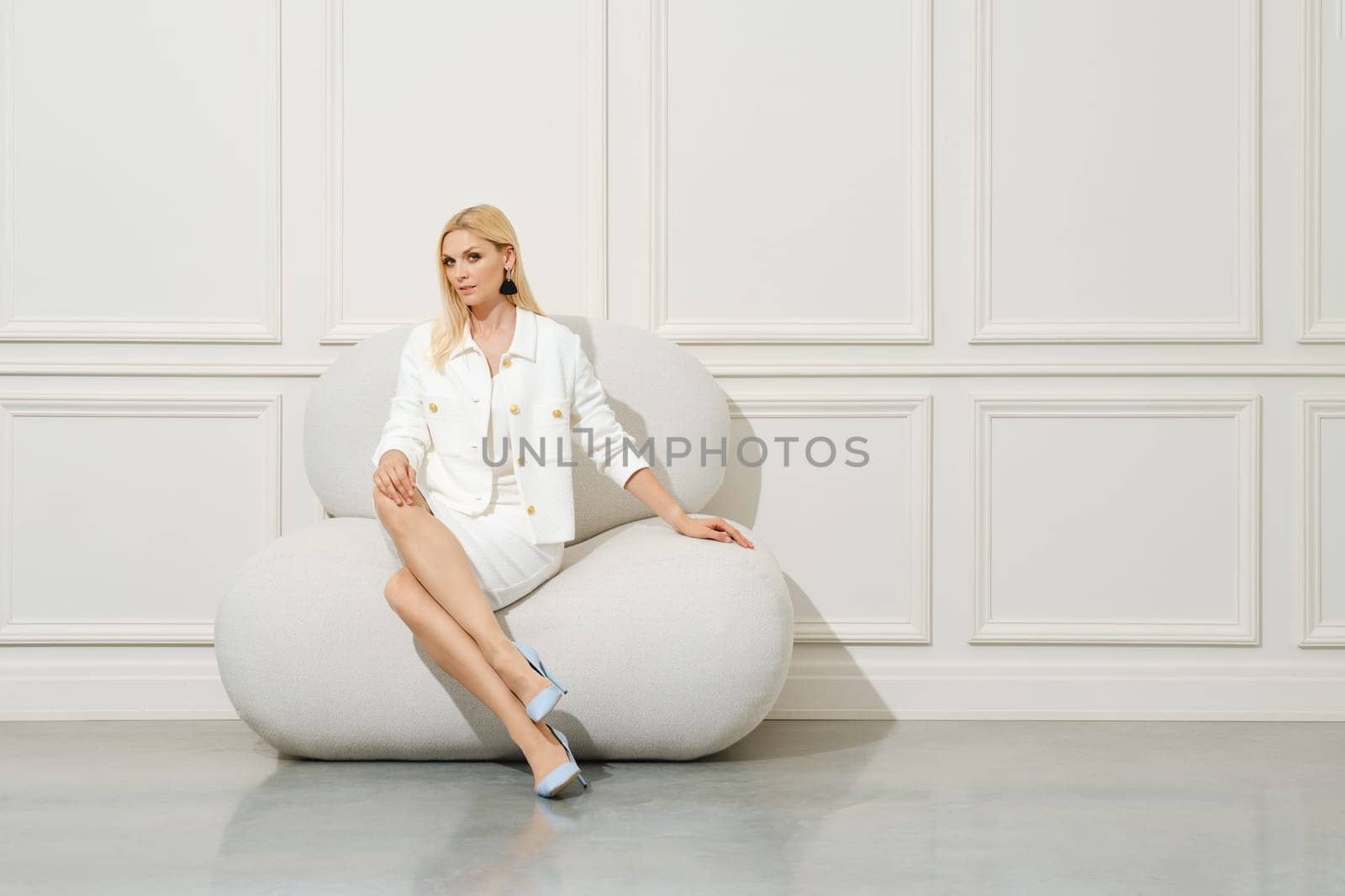 Classy woman in white woollen jacket, blouse and mini skirt