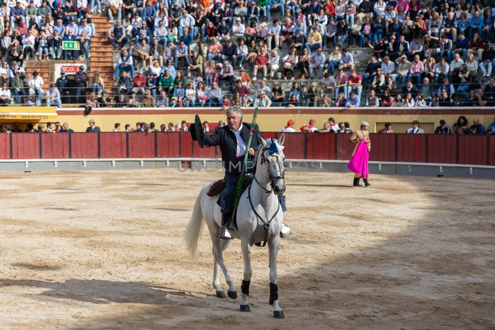March 26, 2023 Lisbon, Portugal: Tourada - a bullfighter on horseback greets spectators from the arena holding a spear. Mid shot