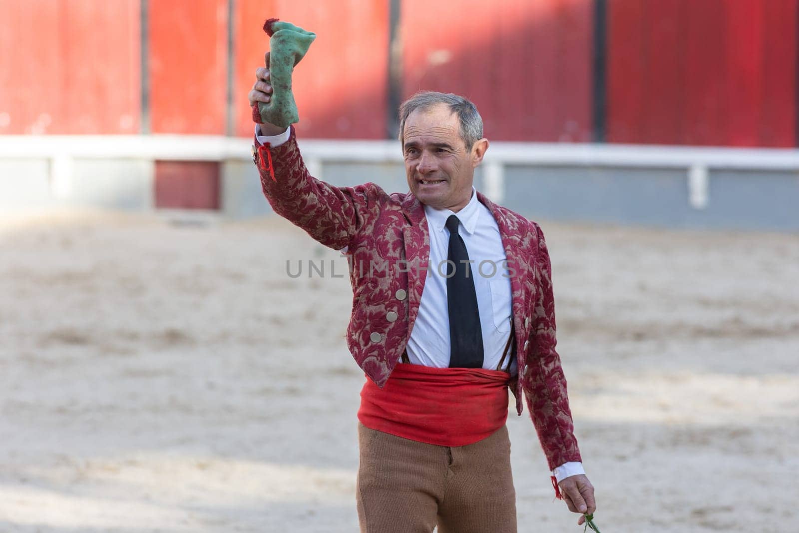 March 26, 2023 Lisbon, Portugal: Tourada - scratched elderly male tereador on the arena with his hand up holding a handkerchief. Mid shot