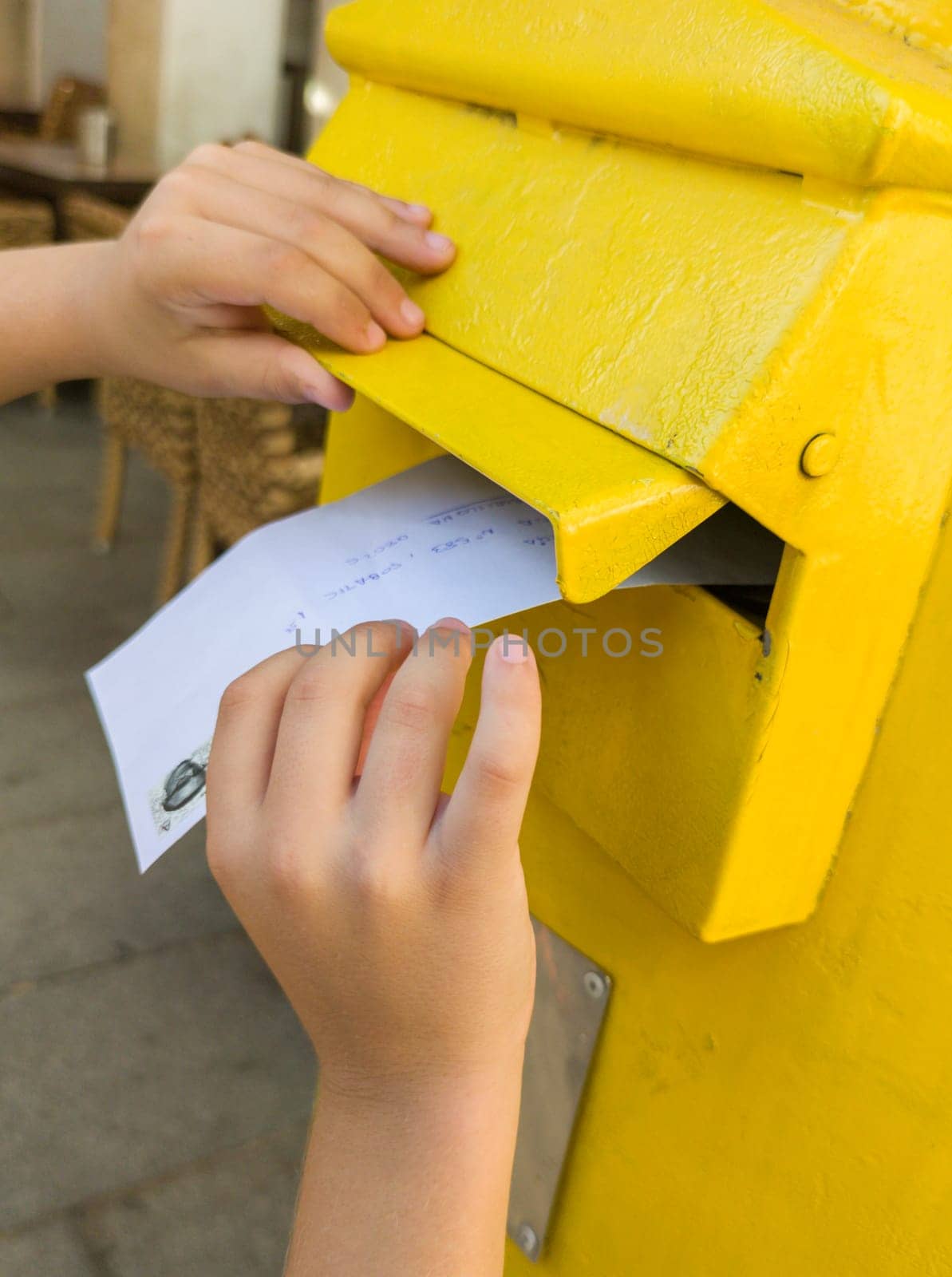 Boy putting a letter in the spanish yellow traditional mailbox. Selective focus