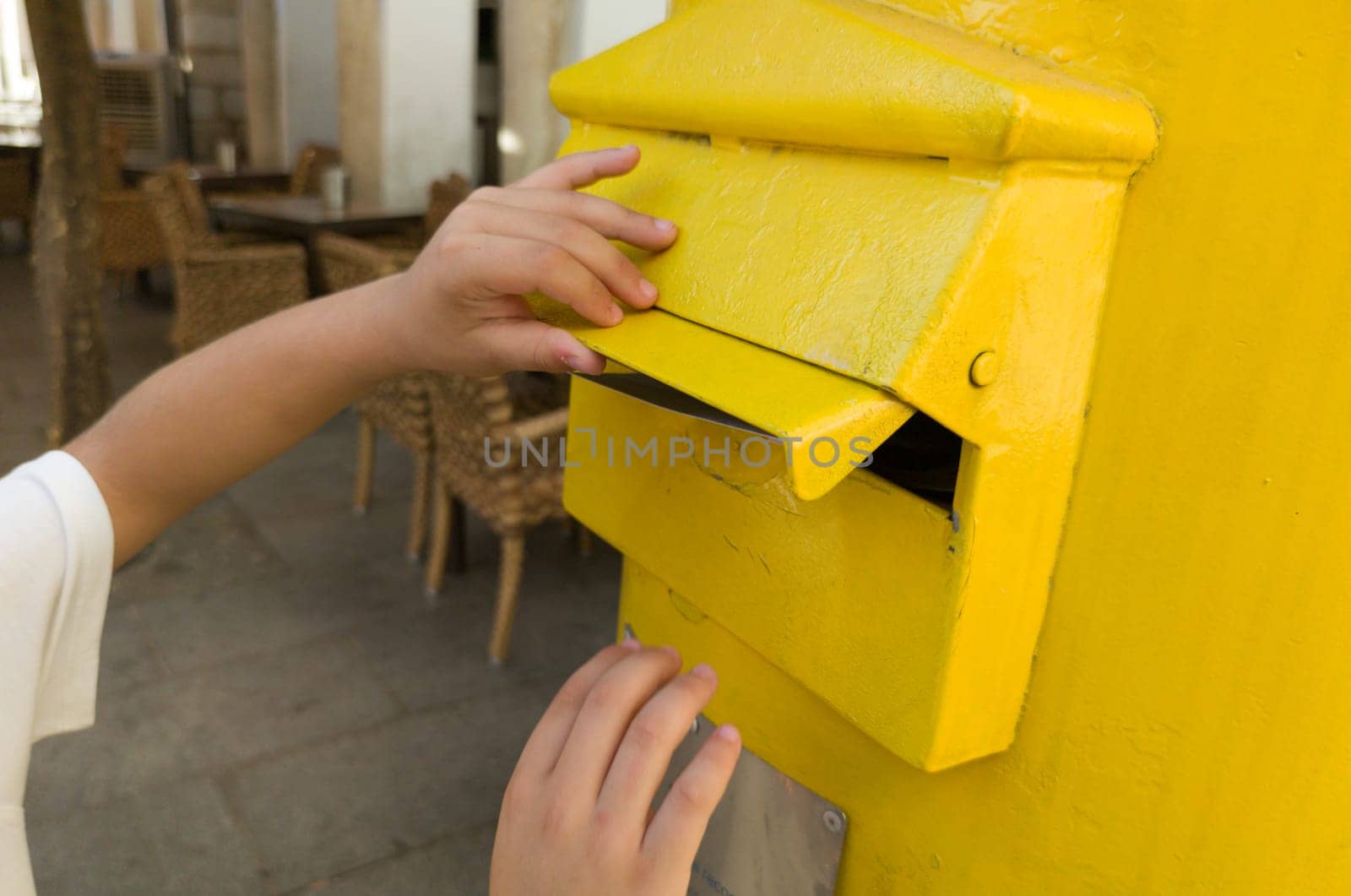 Boy putting a letter in the spanish yellow traditional mailbox. Selective focus