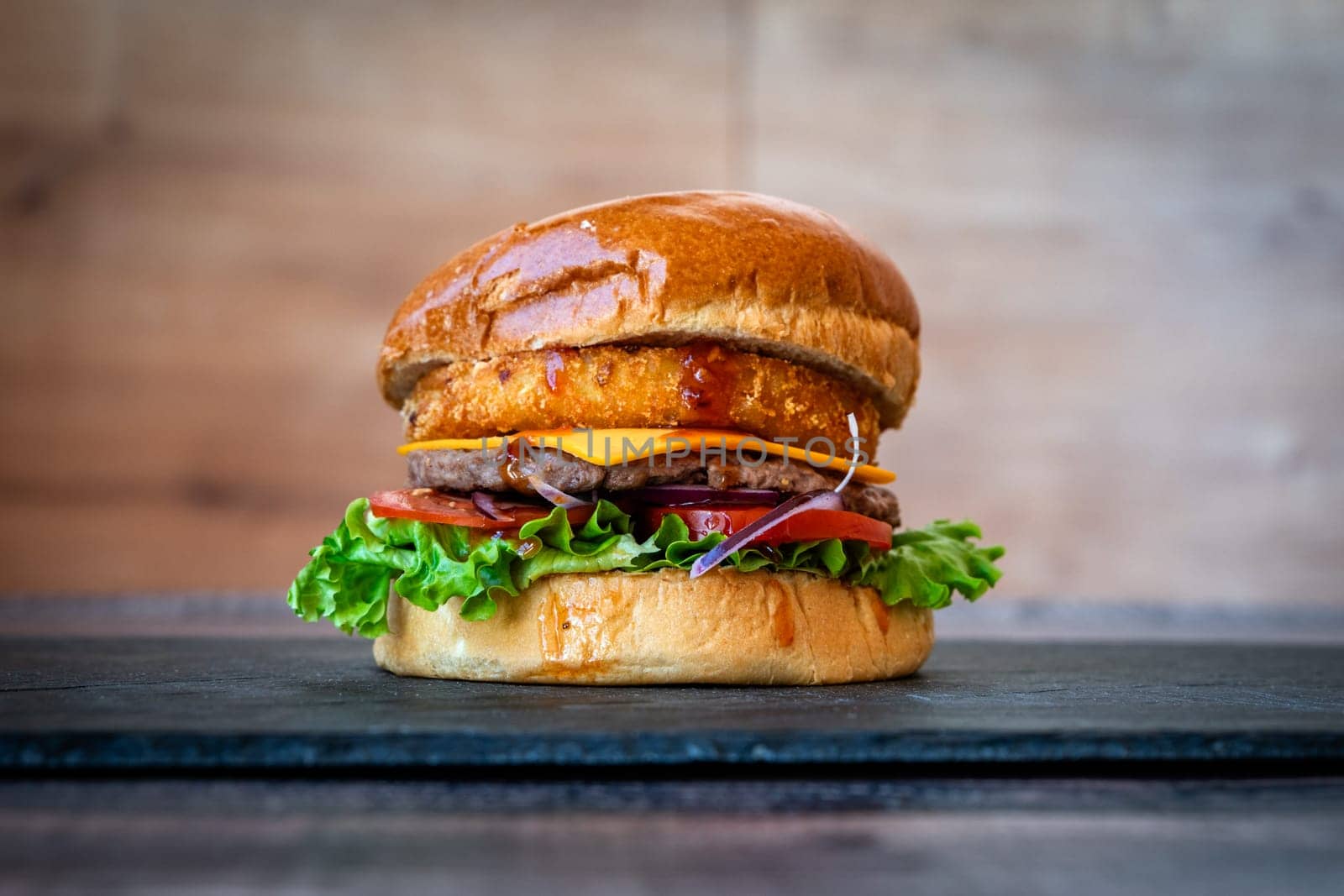 beef burger with sesame lettuce bun tomato cheddar cheese on black background