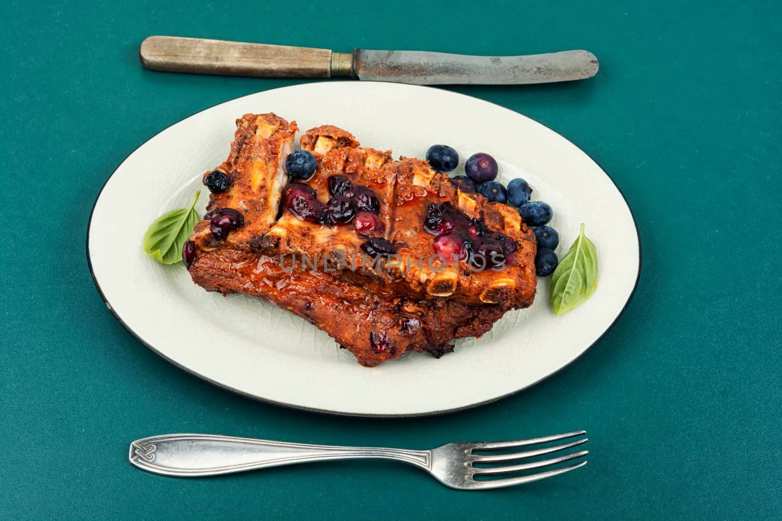 Fried pork ribs with blueberry sauce on a stone background