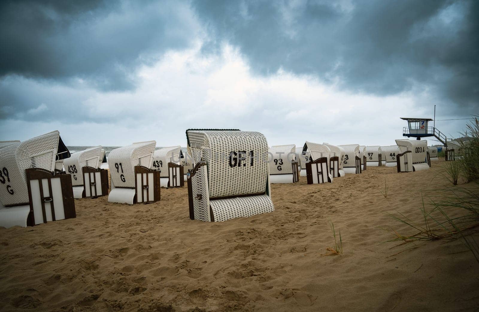 Roofed wicker beach chairs at the baltic sea beach, coast at the island of Usedom in Germany, storm and rain over the brackish water, high waves, storm warning