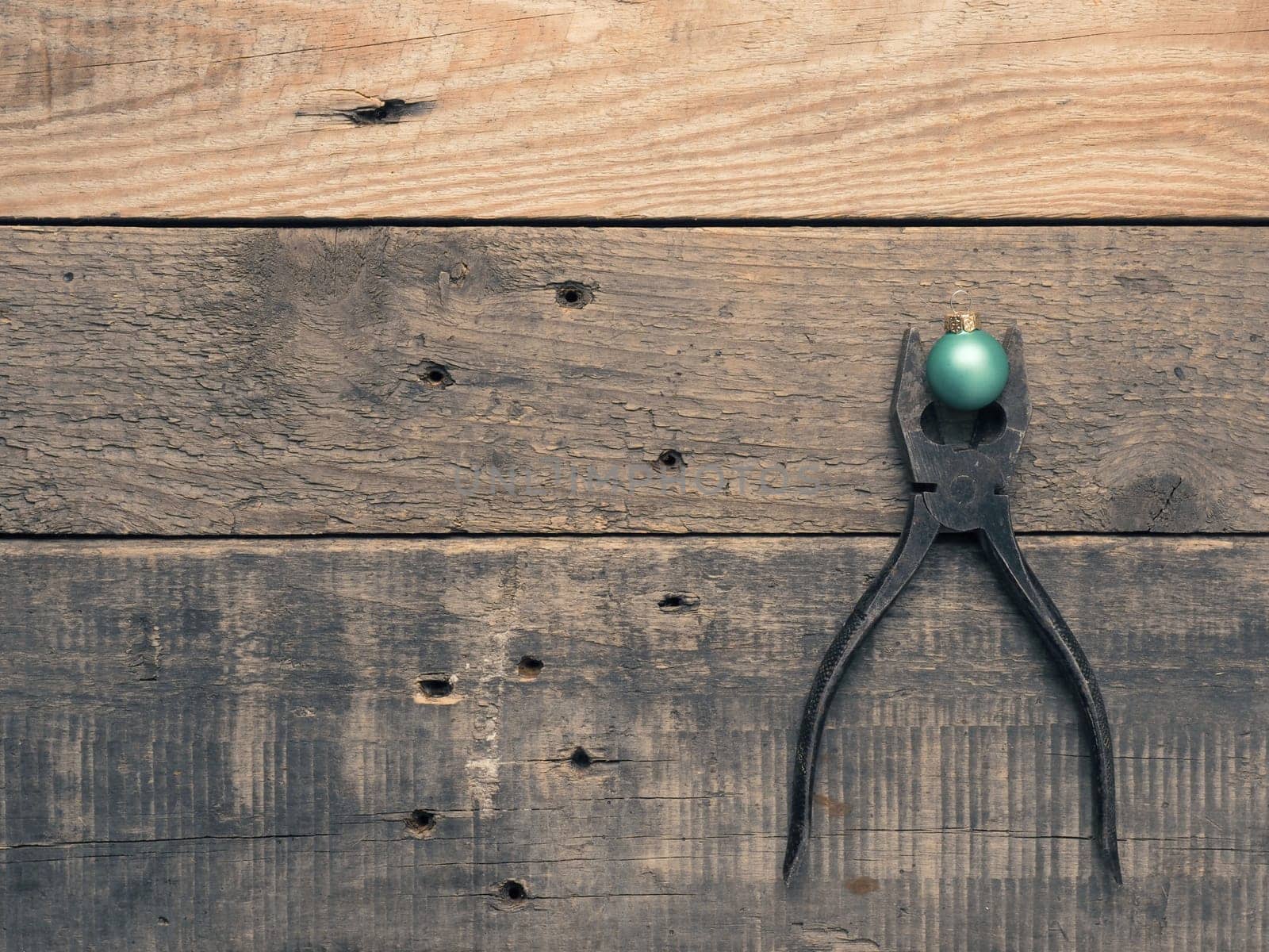 Rusty old pliers with a golden tree shape and Christmas bauble on rustic wood