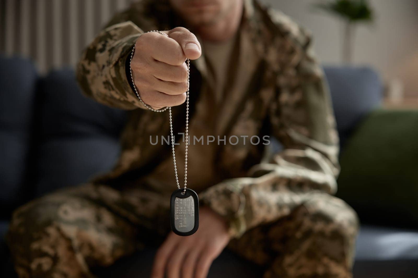 Closeup military hand holding metallic badge dog tag with qr code. Mourning for dead brothers in war