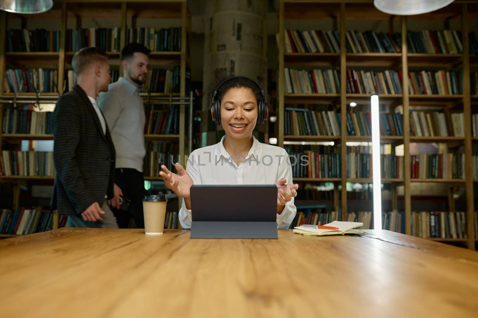 Female office worker wearing headphones working online looking at laptop computer. Watching educational webinar, holding video call with client, virtual meeting with partner concept