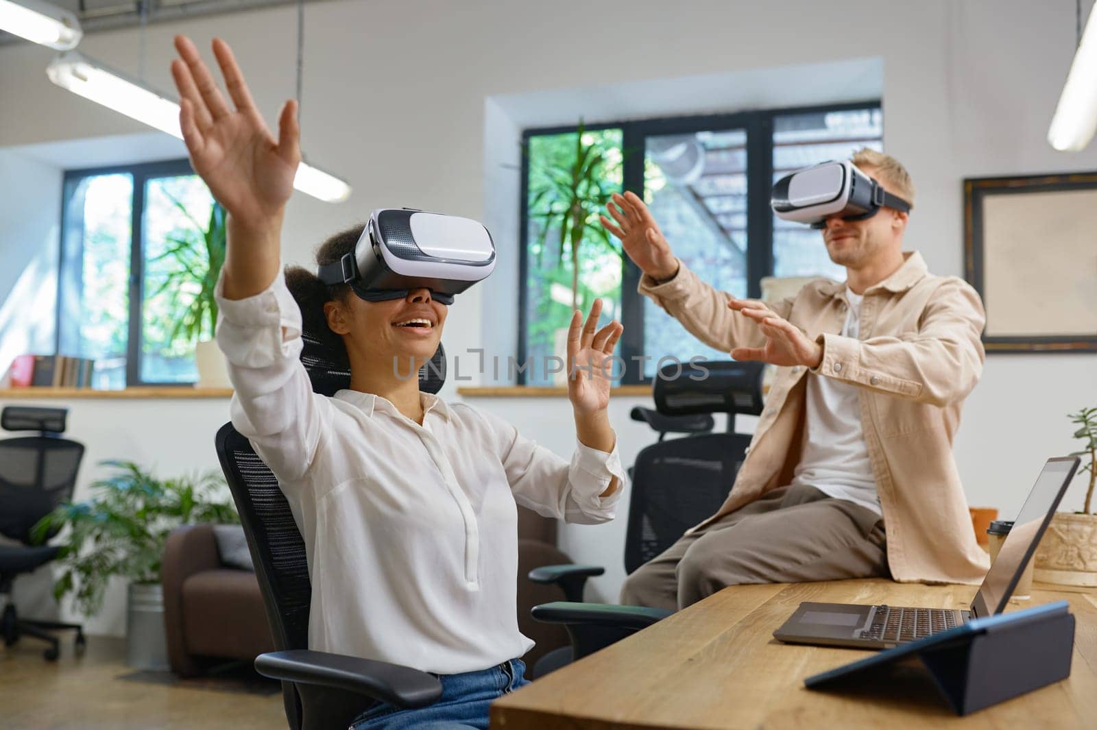 Inspired man and woman coworker wearing vr goggles in office. Male and female colleagues in virtual reality headset playing online games using cyberspace for business meeting and communication