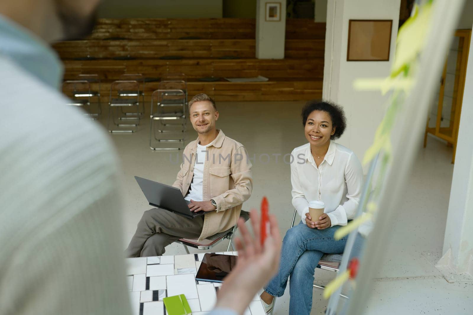 Business meeting or training class in office conference room. Focus on diverse international team of colleagues or student listening presentation of male speaker