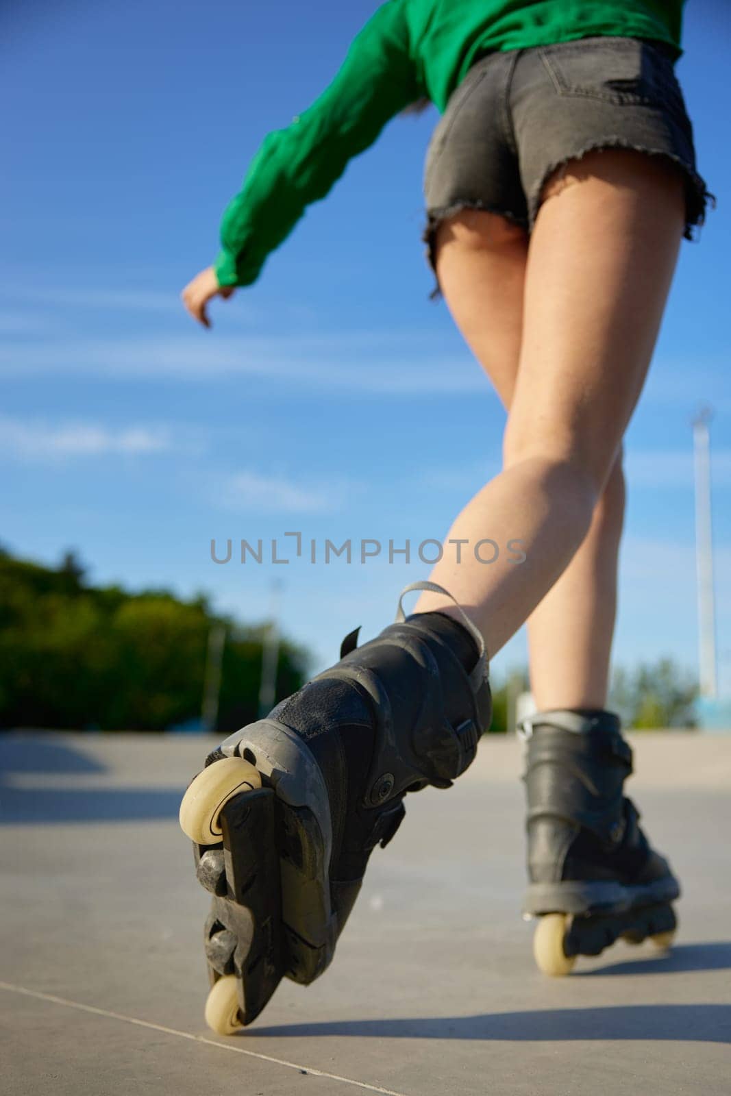 Closeup female legs wearing roller skates over asphalt rollerdrom background. Summer recreation time