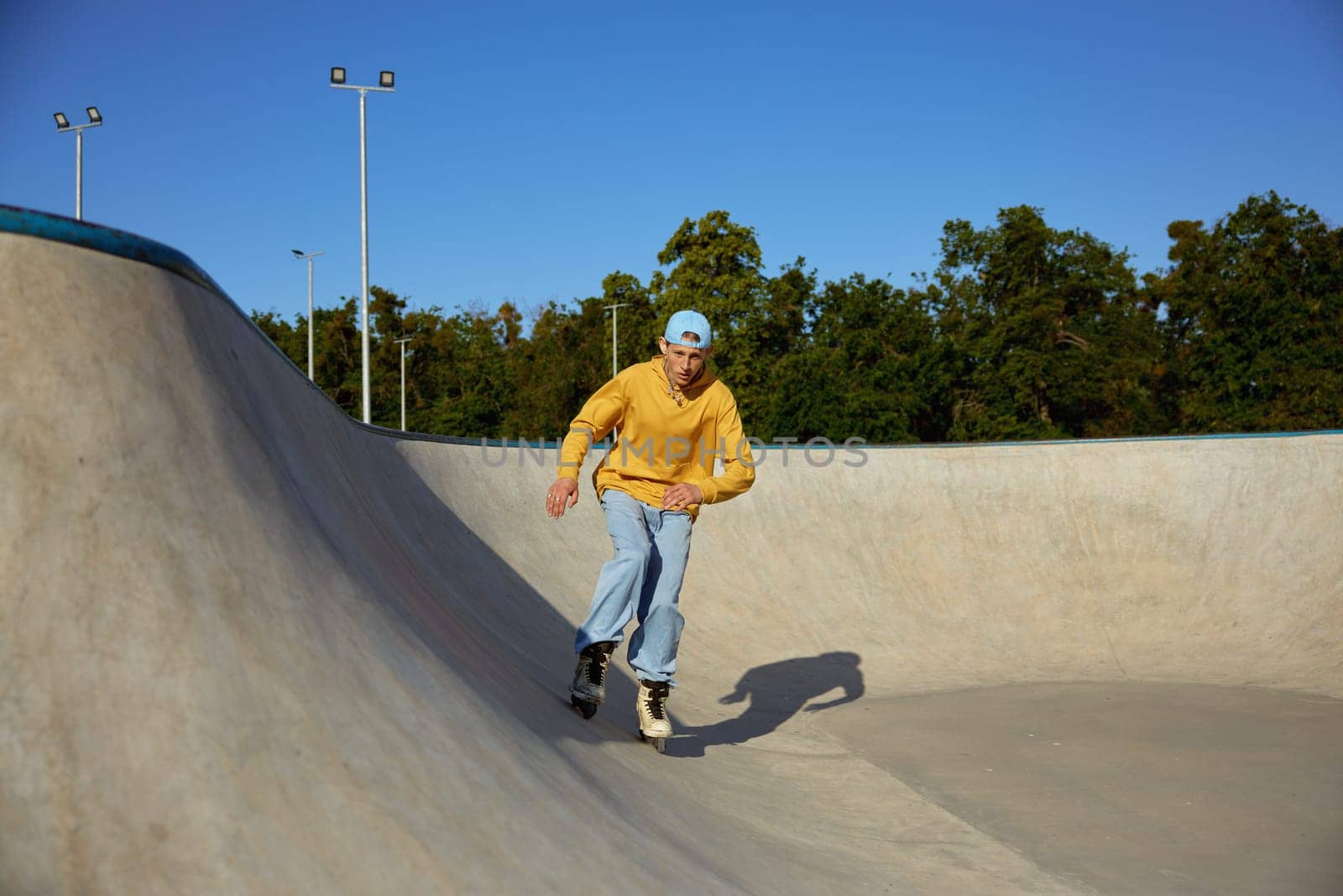 Skilled teenager boy wearing casual clothing and in roller blades riding on ramp. Inline skates sport