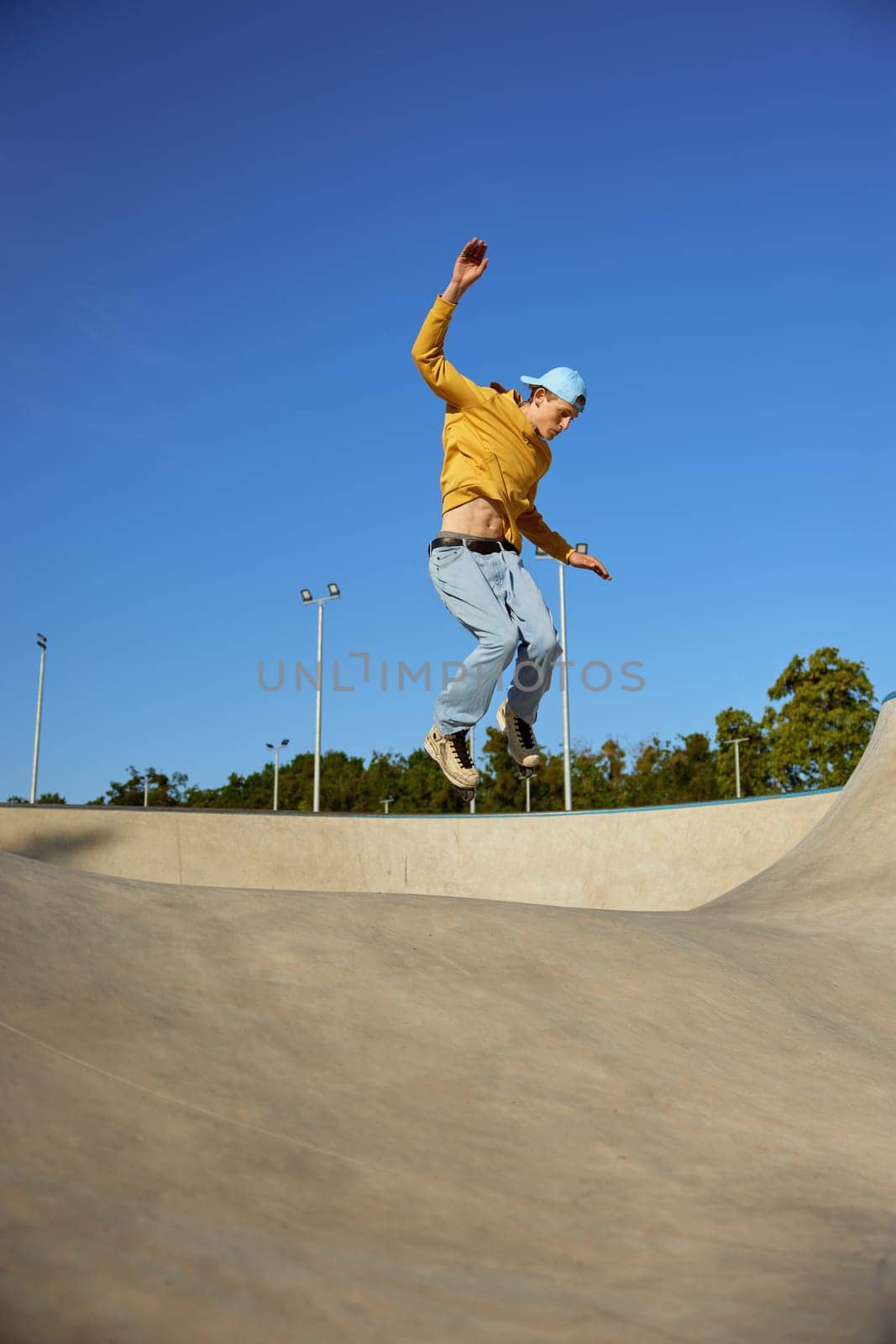 Skilled teenager boy wearing casual clothing and in roller blades jumping on ramp. Inline skates sport