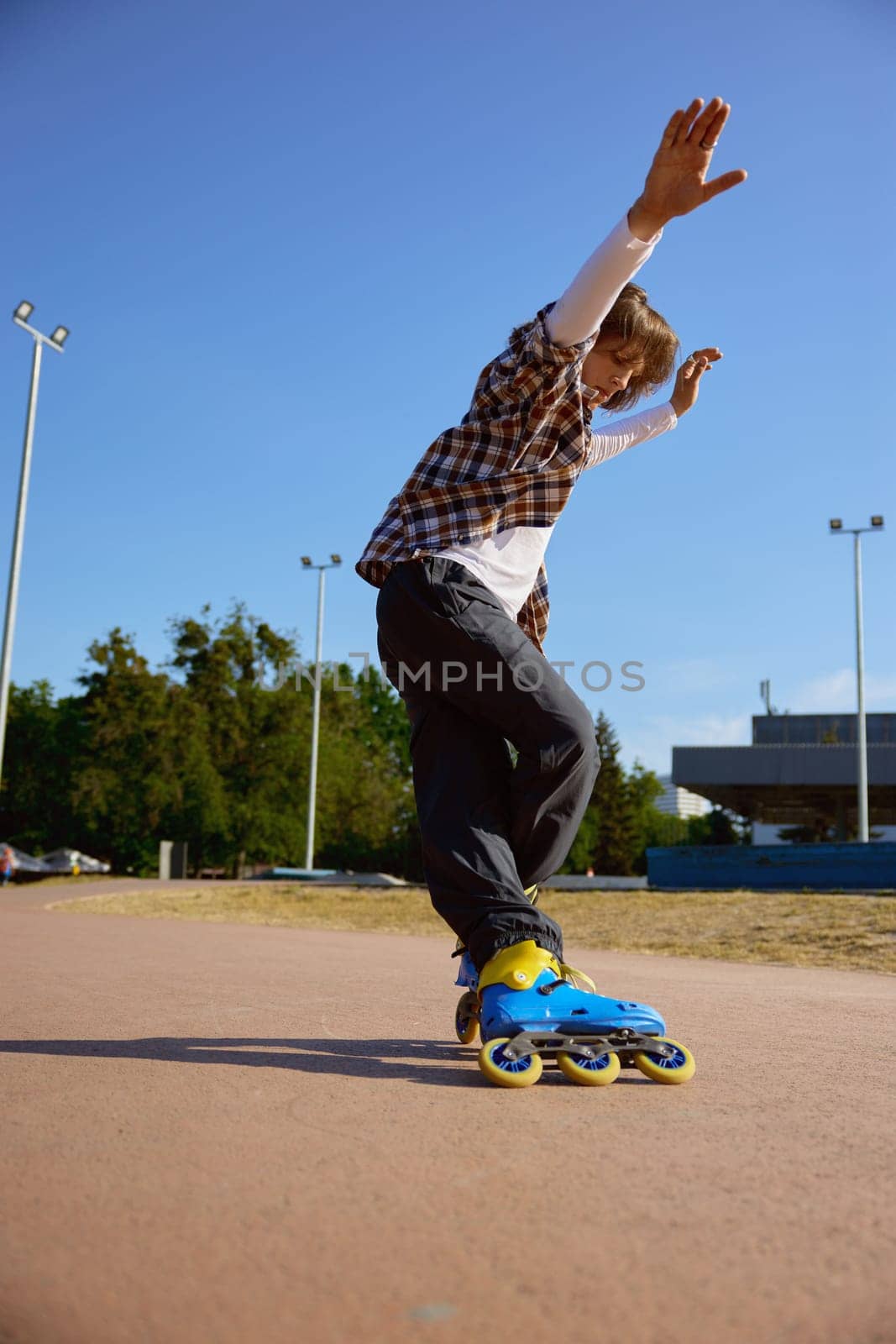Active schoolboy rollerblading on street having training class for practicing free riding