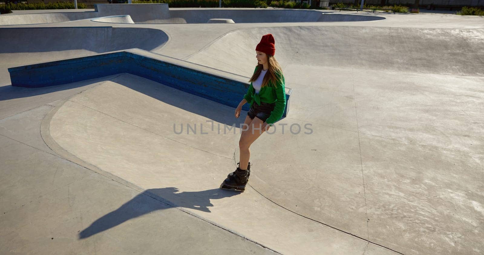 Active young woman on roller skates enjoying freestyle riding on rollerdrom. Physical activity in weekend