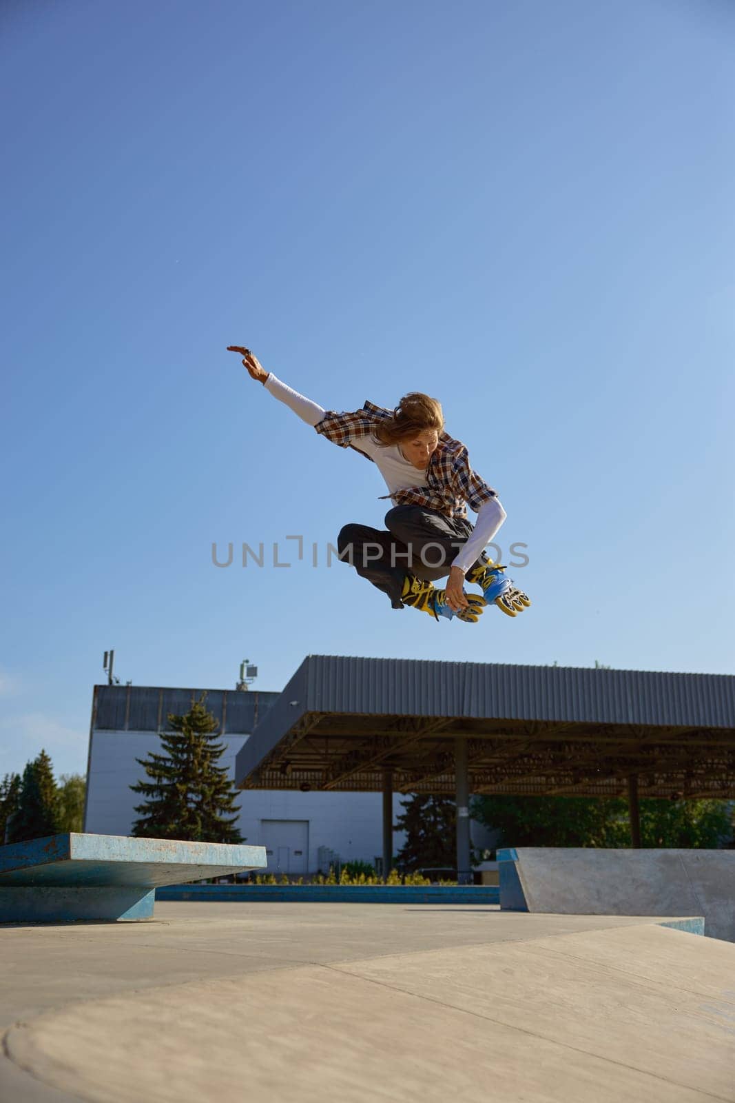 Roller skating concept, young male skater jumping high on ramp. Teenager boy enjoying speed rollerblading in park