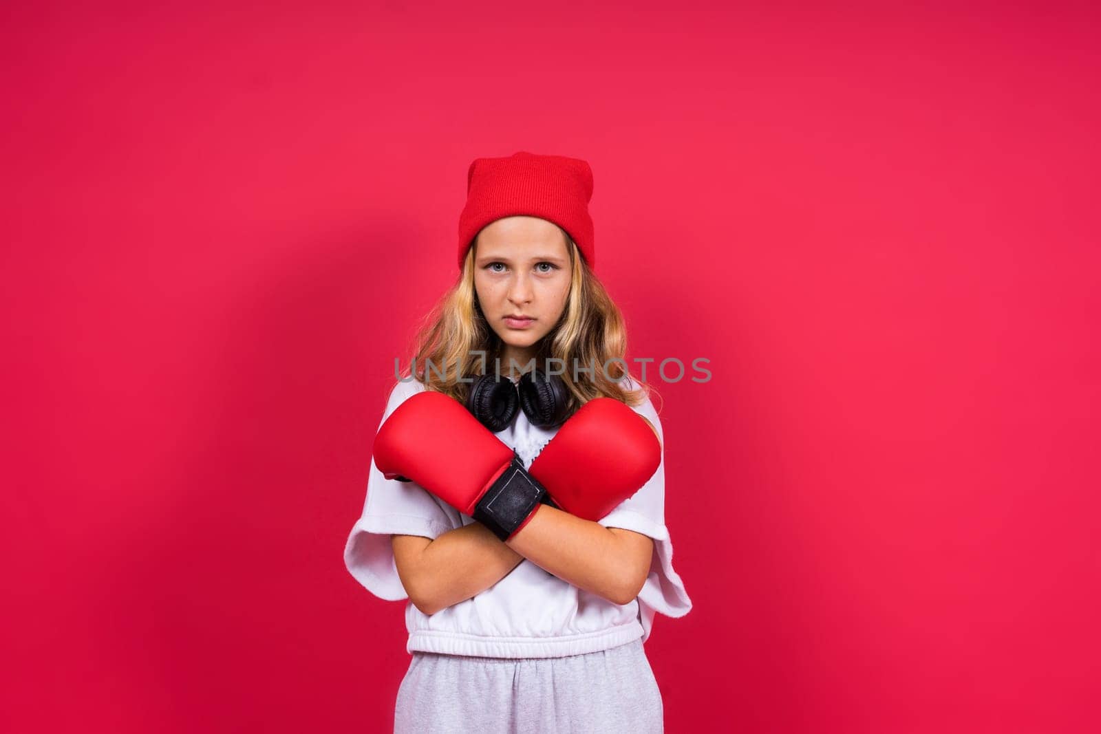 Cute little girl in boxing gloves on a red background studio