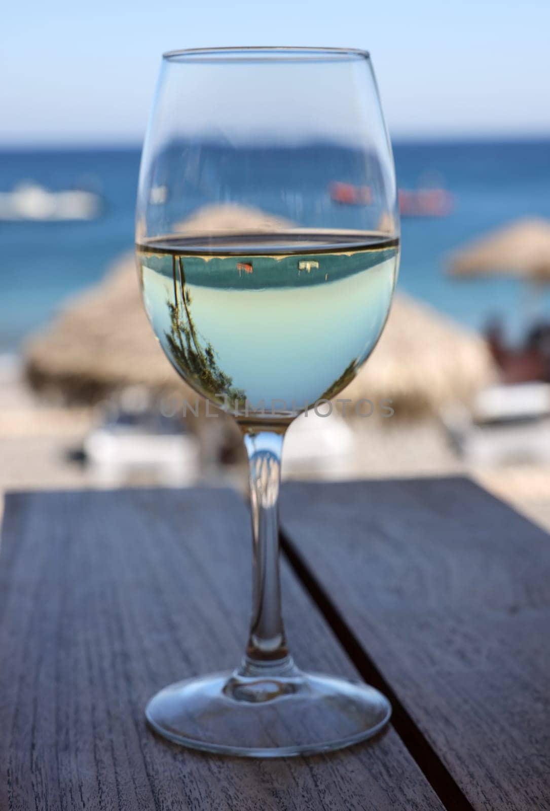 A glass of white wine at a restaurant by the beach in Kamari, Santorini. Greece