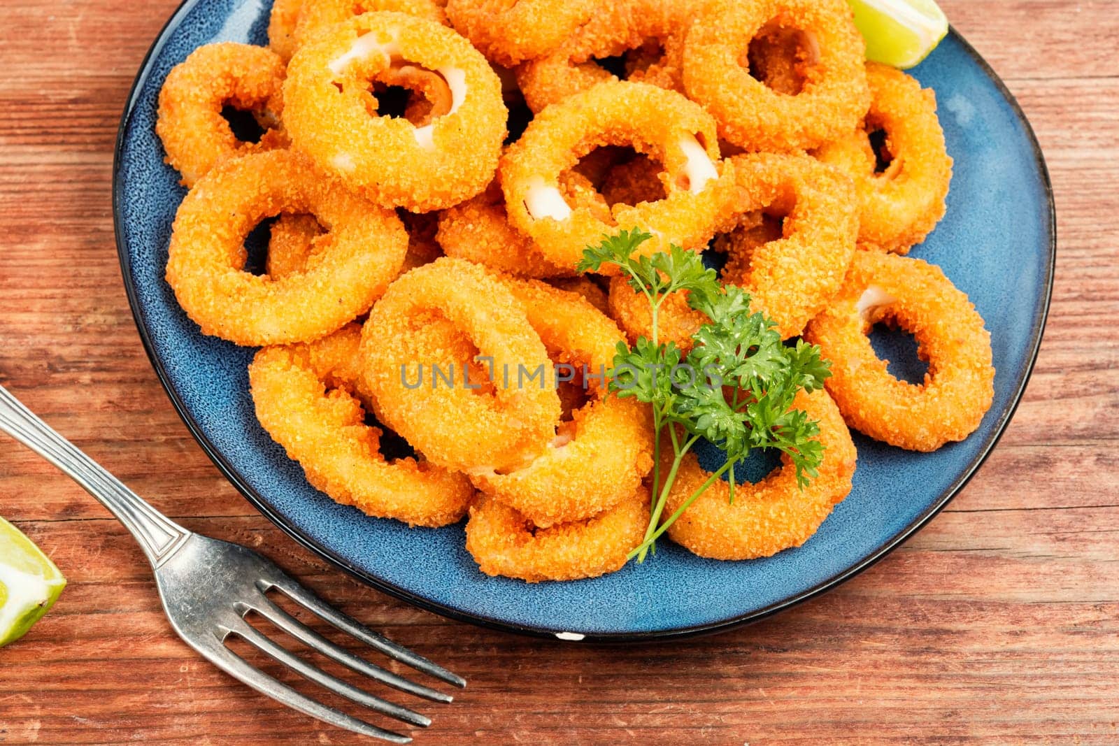 Deep fried calamari or squid rings on old wooden table.. Delicious fried food