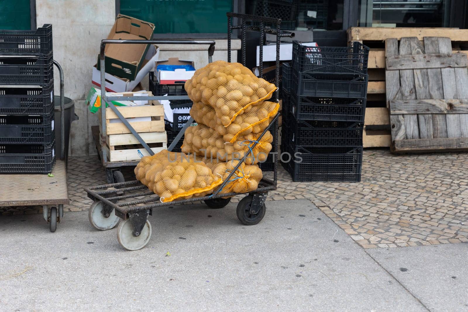 Sacks of potatoes on the street by other containers. Mid shot