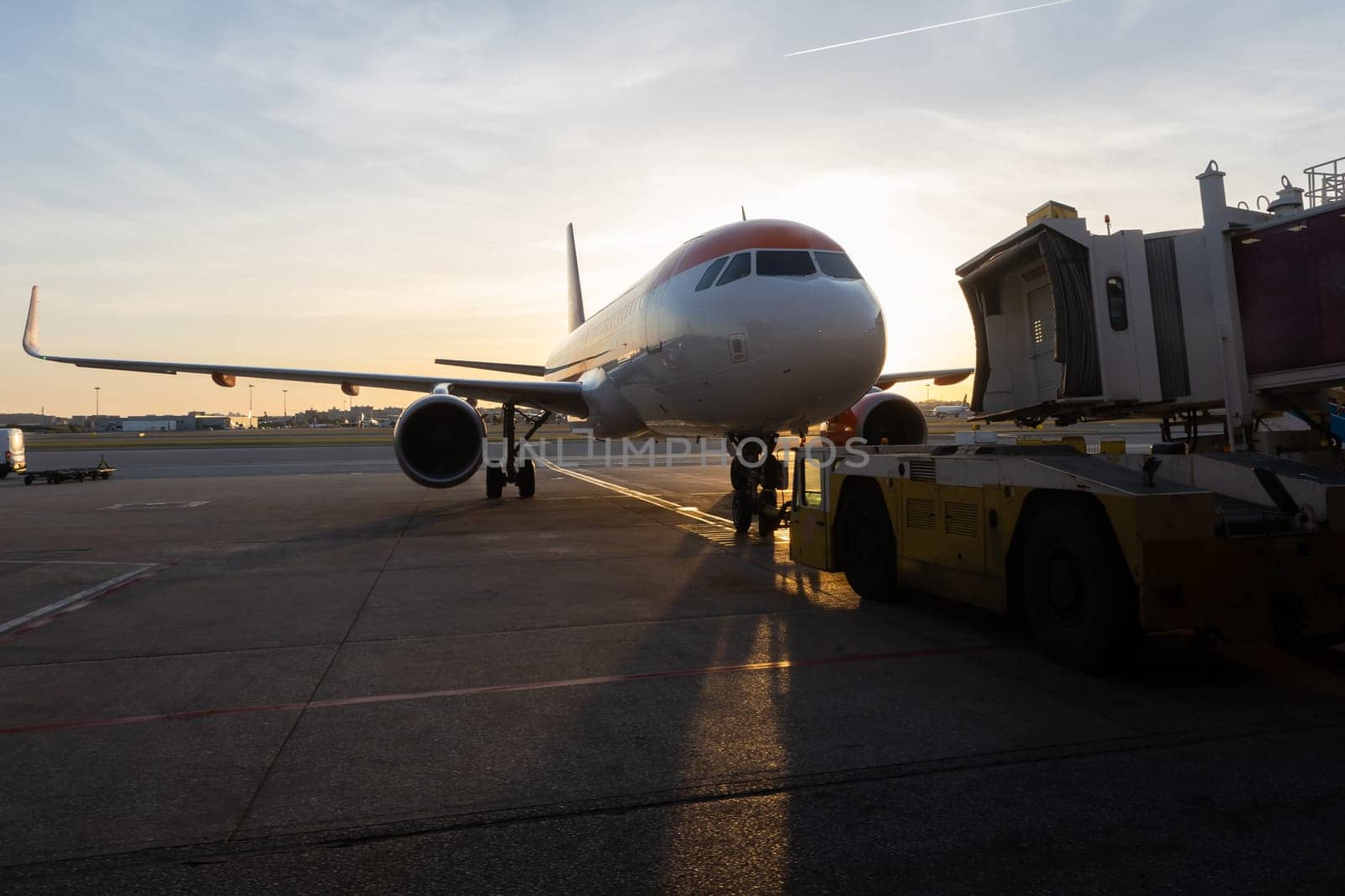 A jet bridge connecting to an airplane at sunset. Mid shot