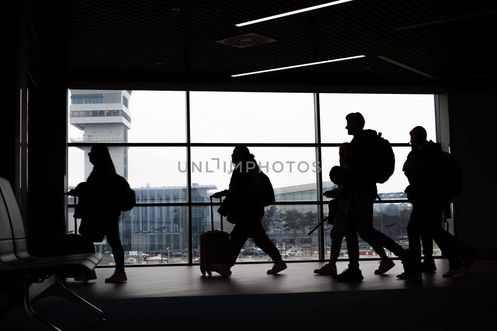 Silhouettes of tourists walking at the airport. Mid shot