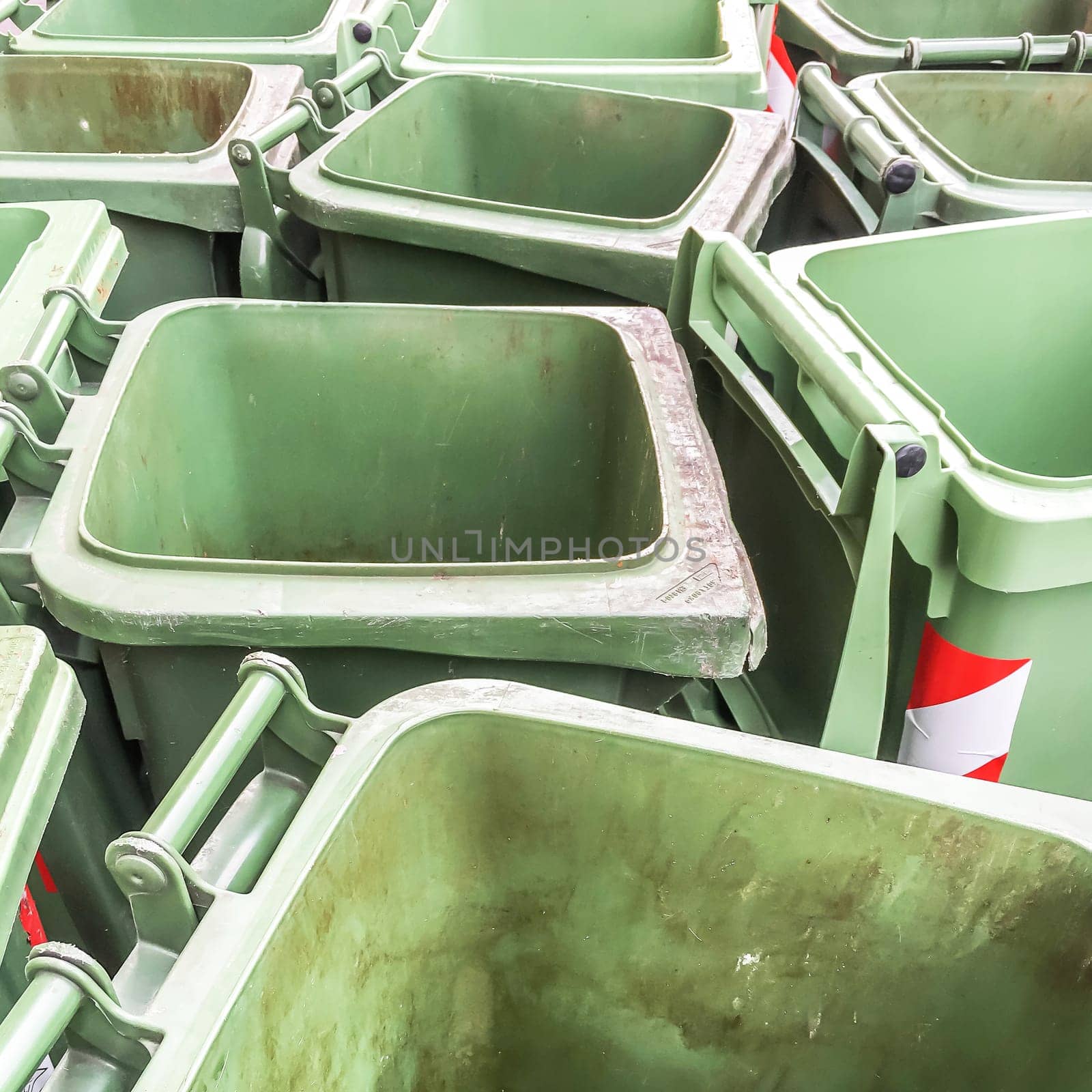 Row of empty green rubbish bins on the street.