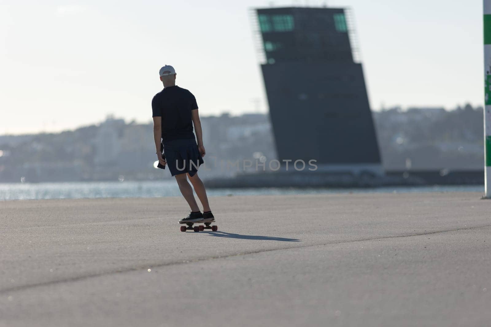 Young man skater training at the waterfront. Mid shot