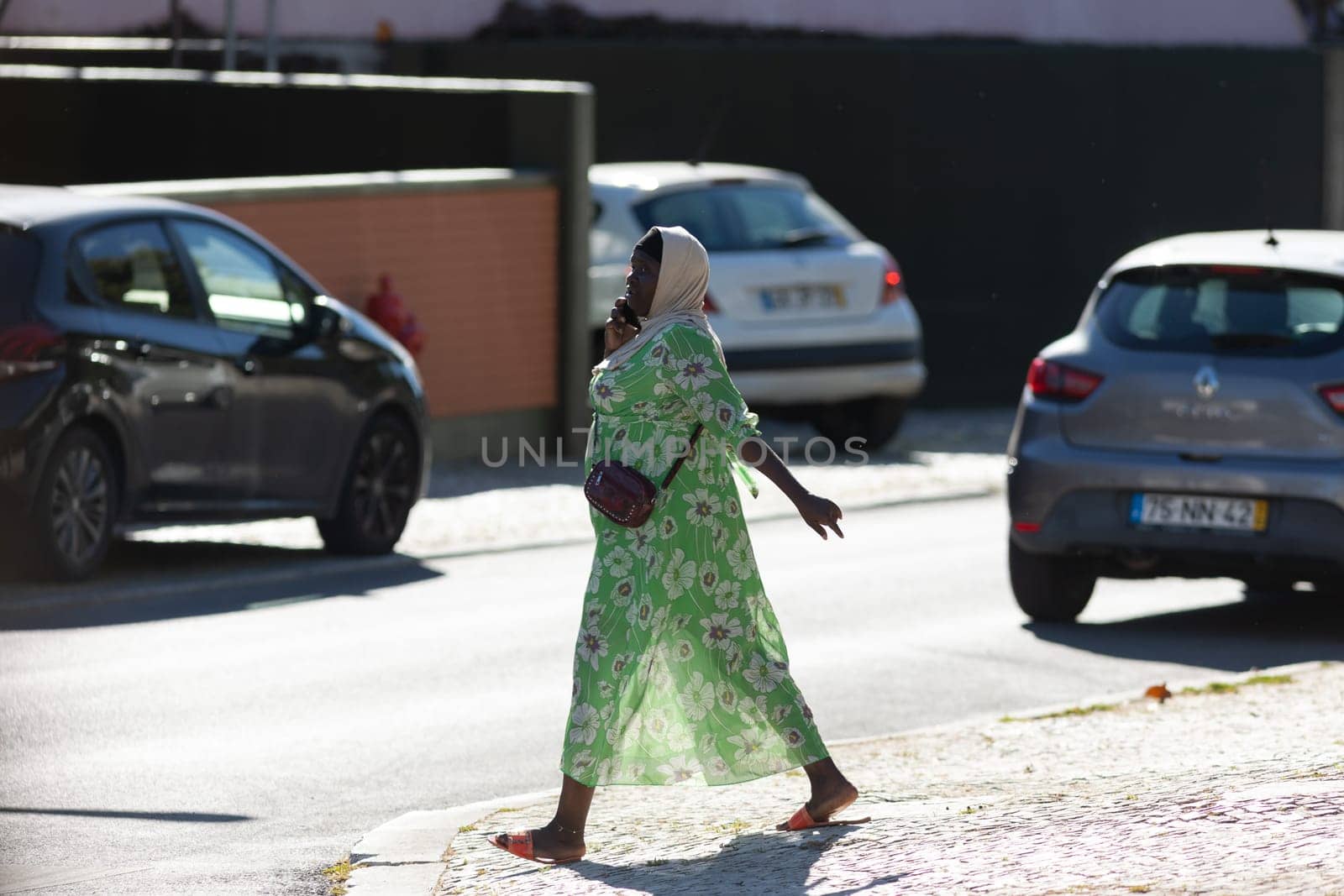 11 April 2023 Lisbon, Portugal: black woman walking on street talking on her phone. Mid shot