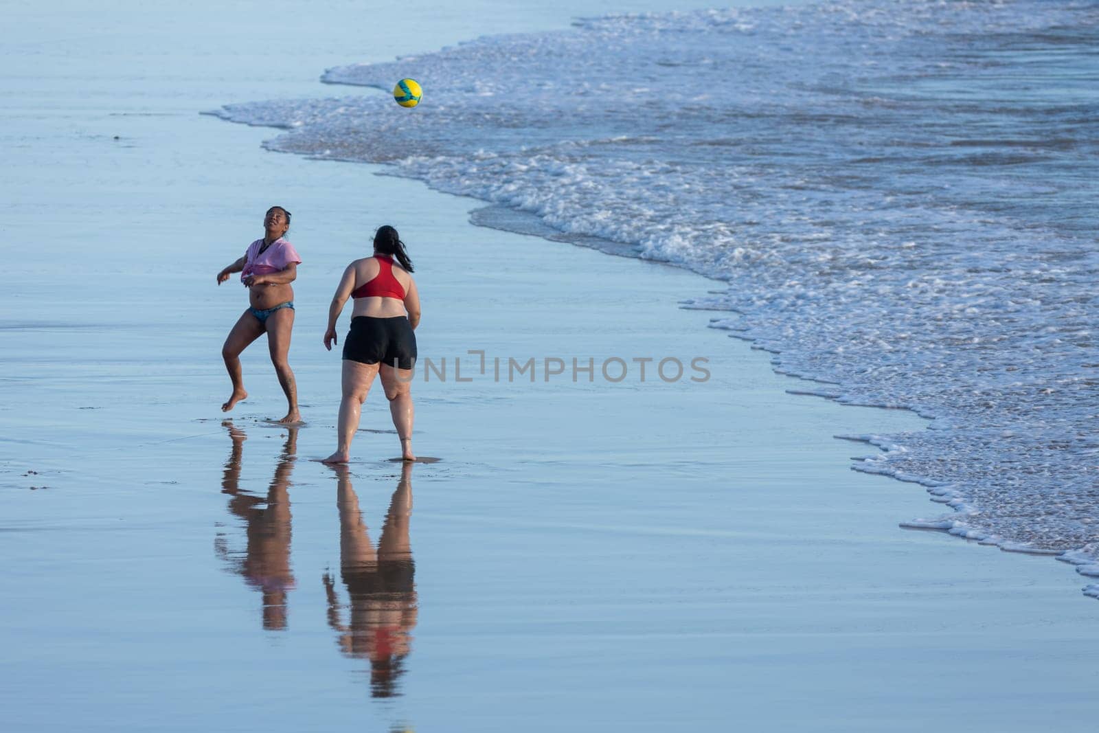 19 April 2023 Lisbon, Portugal: Costa da Caparica - black and white women playing with ball on the beach. Mid shot
