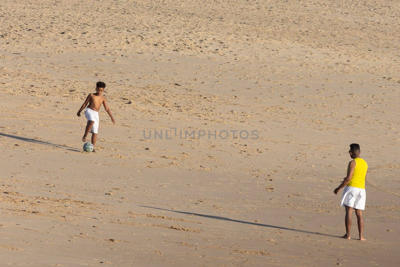 19 April 2023 Lisbon, Portugal: Costa da Caparica - black kids playing with a ball on the beach. Mid shot