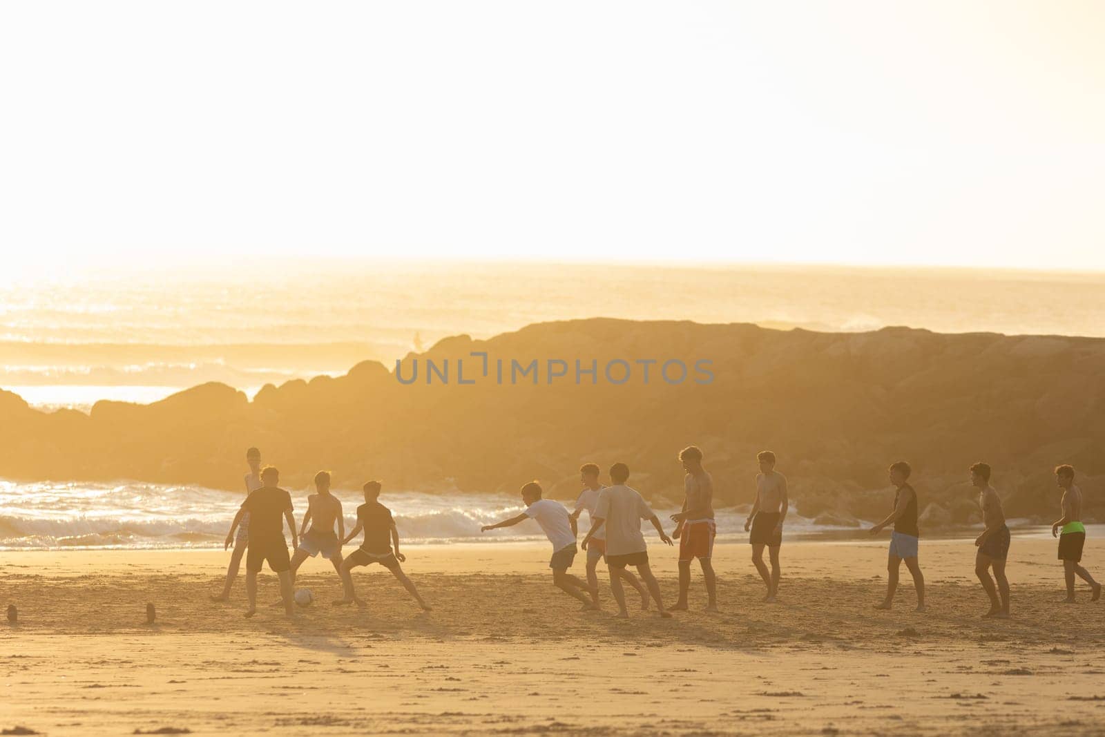 19 April 2023 Lisbon, Portugal: Costa da Caparica - young men playing soccer on the beach at sunset. Mid shot
