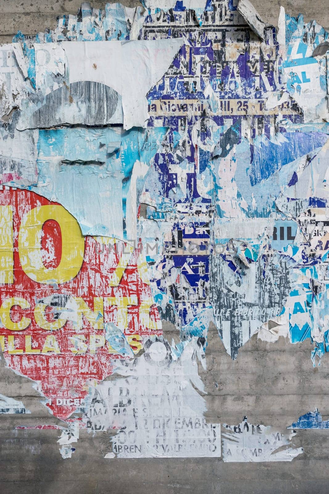 Concrete wall with colorful ripped bill posters. Grunge background