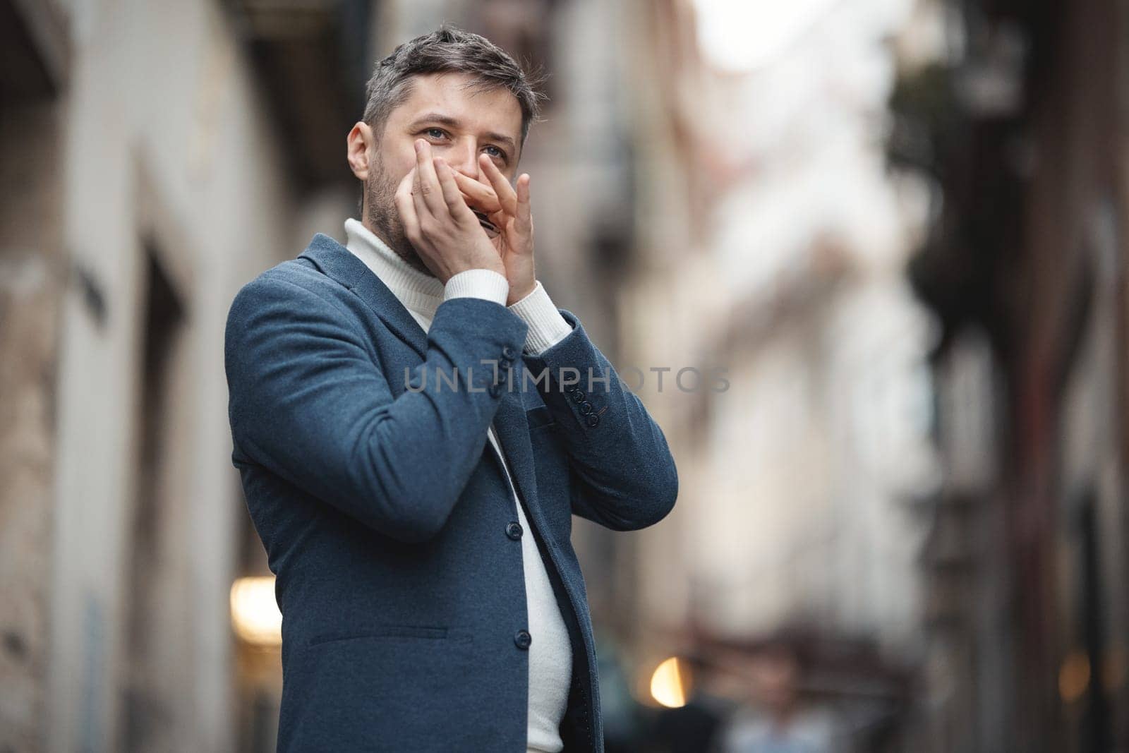 An adult man plays the harmonica on the street. Mid shot