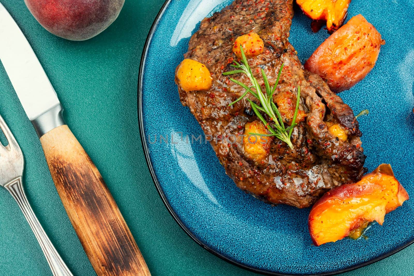 Tasty beef steak with peach in fruit marinade. Close-up.