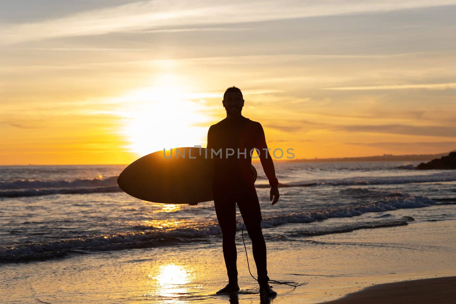 Silhouette of a man surfer on the seashore. Mid shot