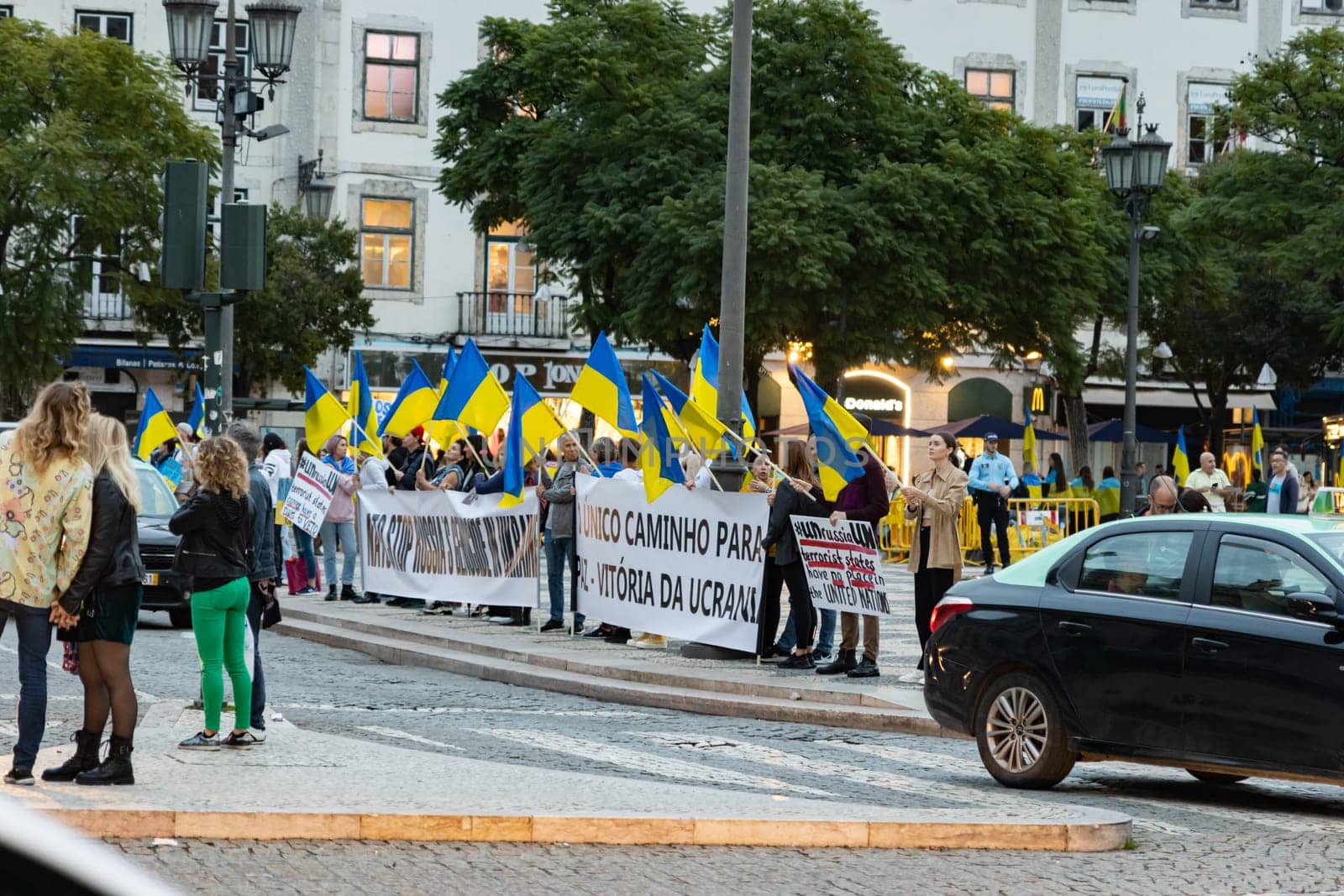 10-29-2022 LISBON, PORTUGAL: Ukrainian protest in Lisbon - people are holding Ukrainian flags and protest posters standing next to the roadway. Mid shot