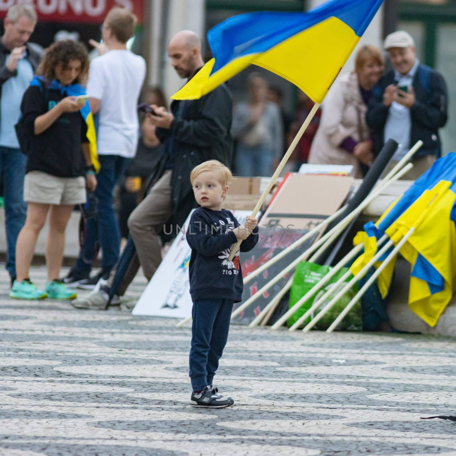 10-29-2022 LISBON, PORTUGAL: Ukrainian protest in Lisbon - a little boy holds a Ukrainian flag in the square during a protest. Mid shot