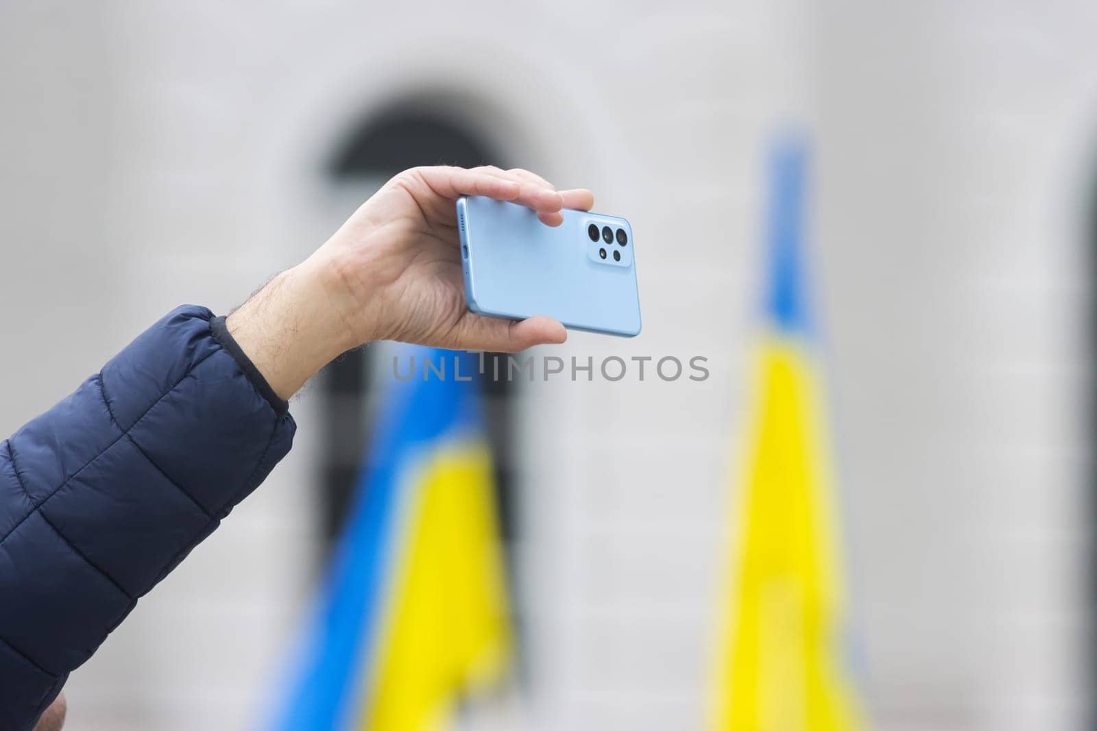 A man shoots a video on his phone at a Ukrainian rally. Mid shot