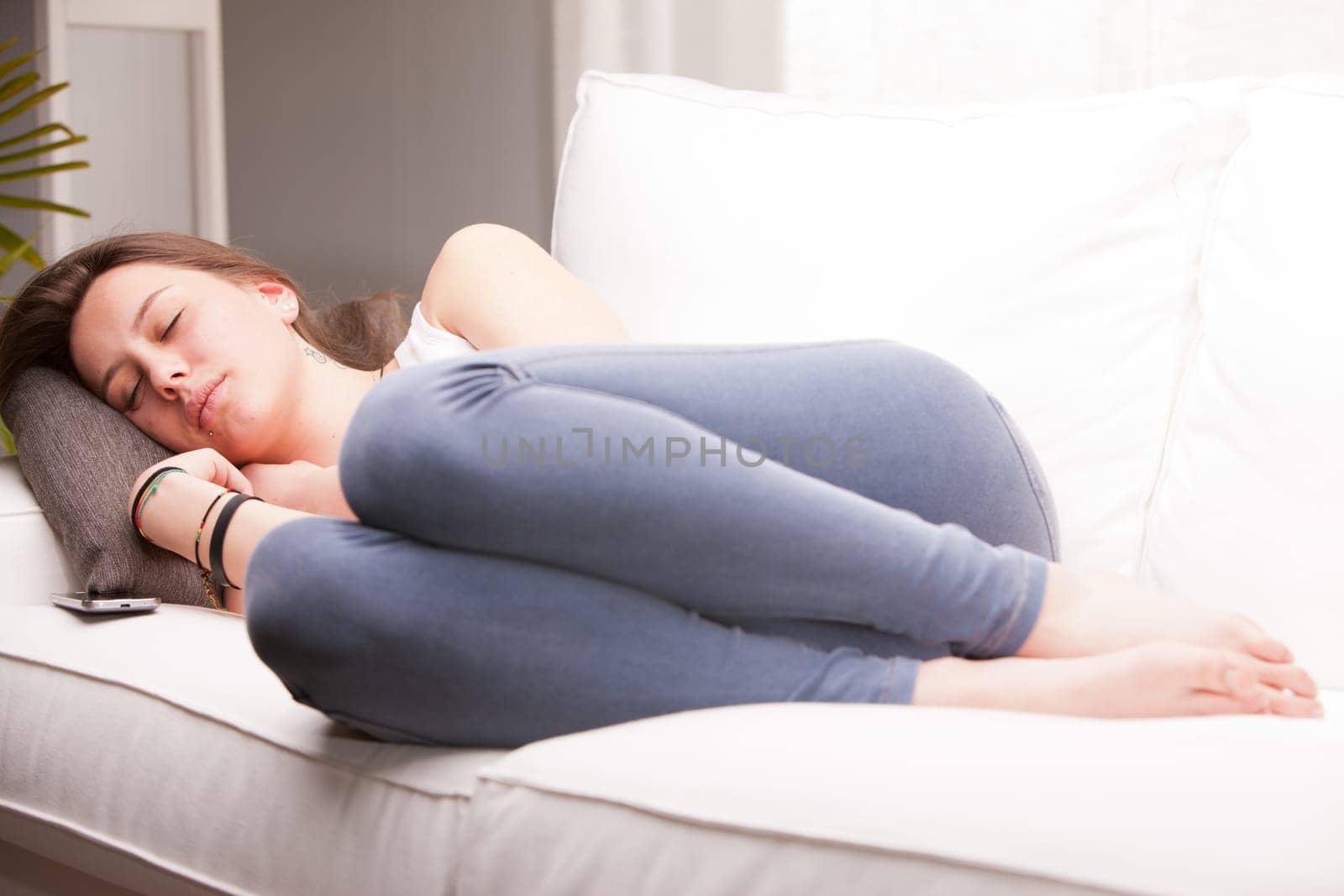 brown haired girl sleeping on her couch in a white living room
